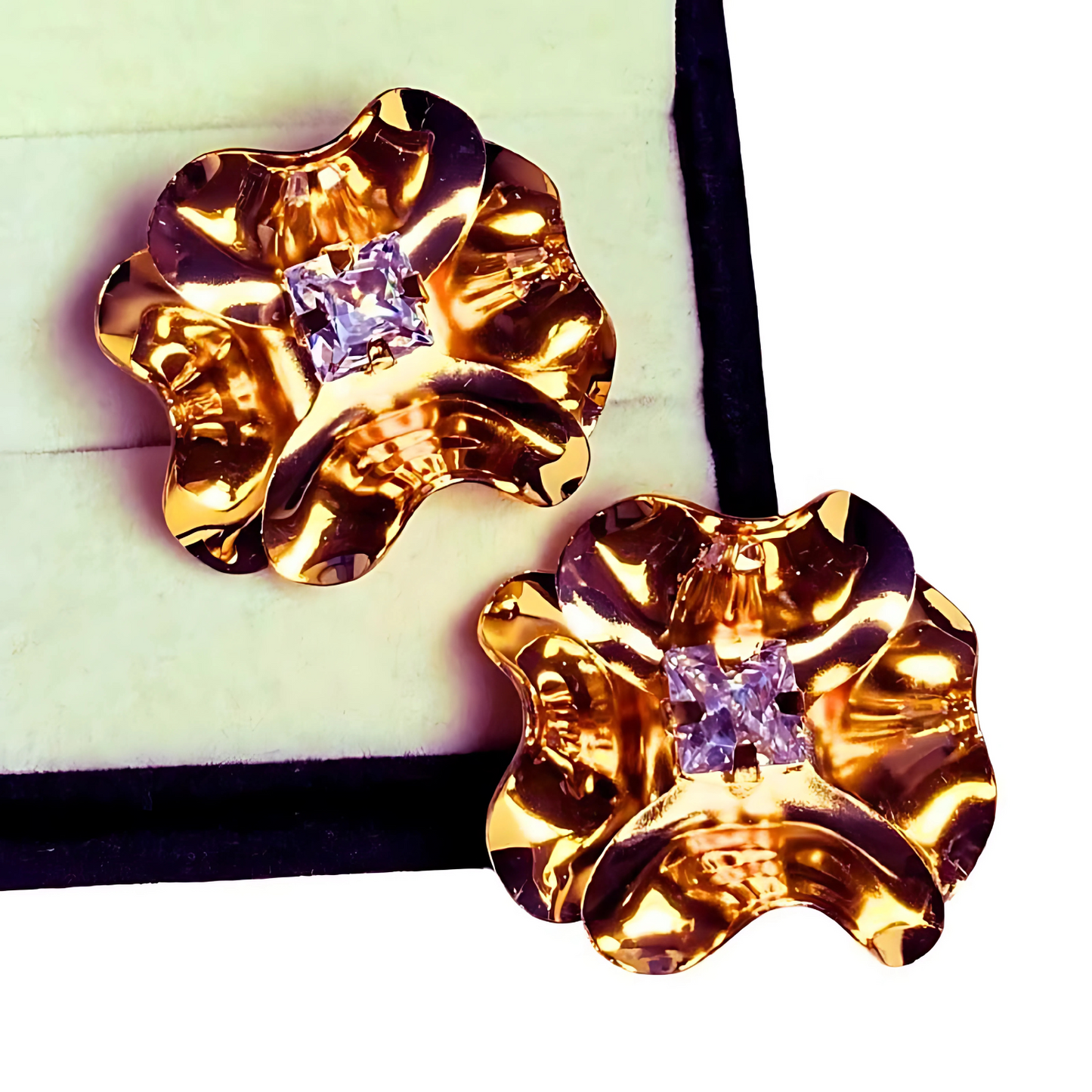 Gold floral earrings with purple gemstones on a white background