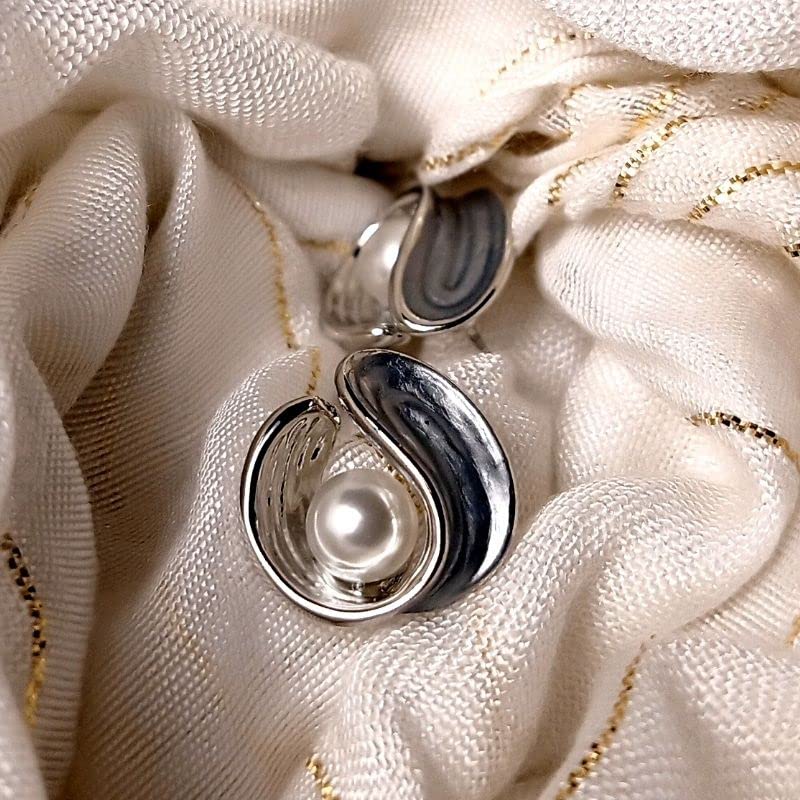 Silver earrings with pearls on a textured white fabric background