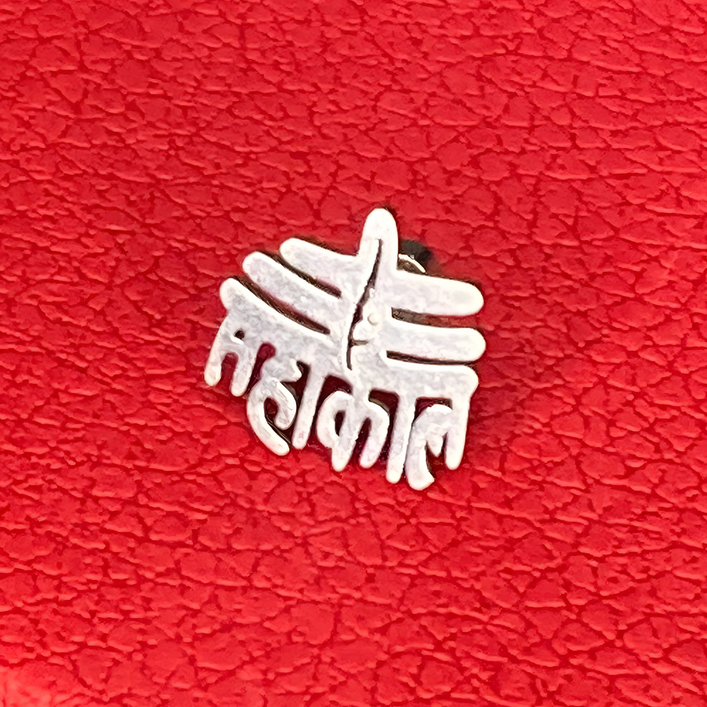 Silver decorative item on a red textured surface
