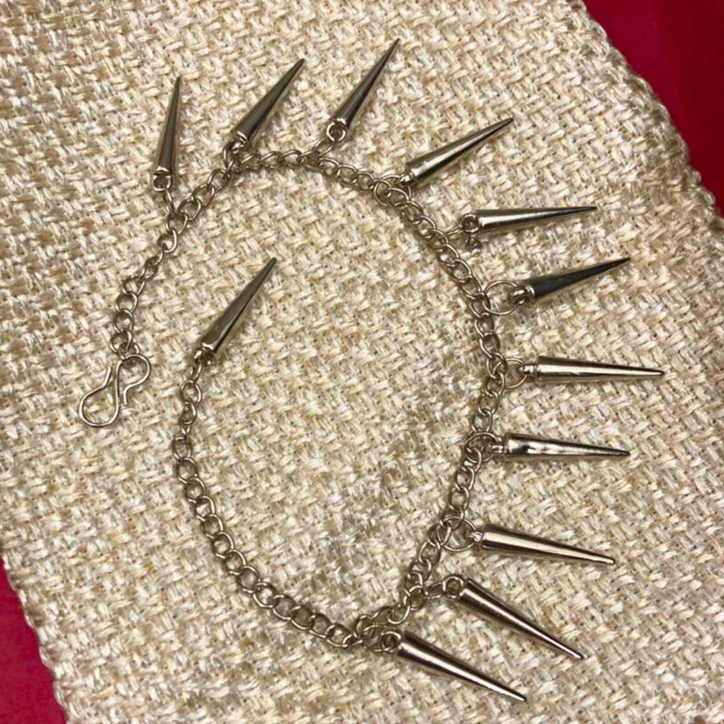 Silver chain choker with spikes on a textured beige surface