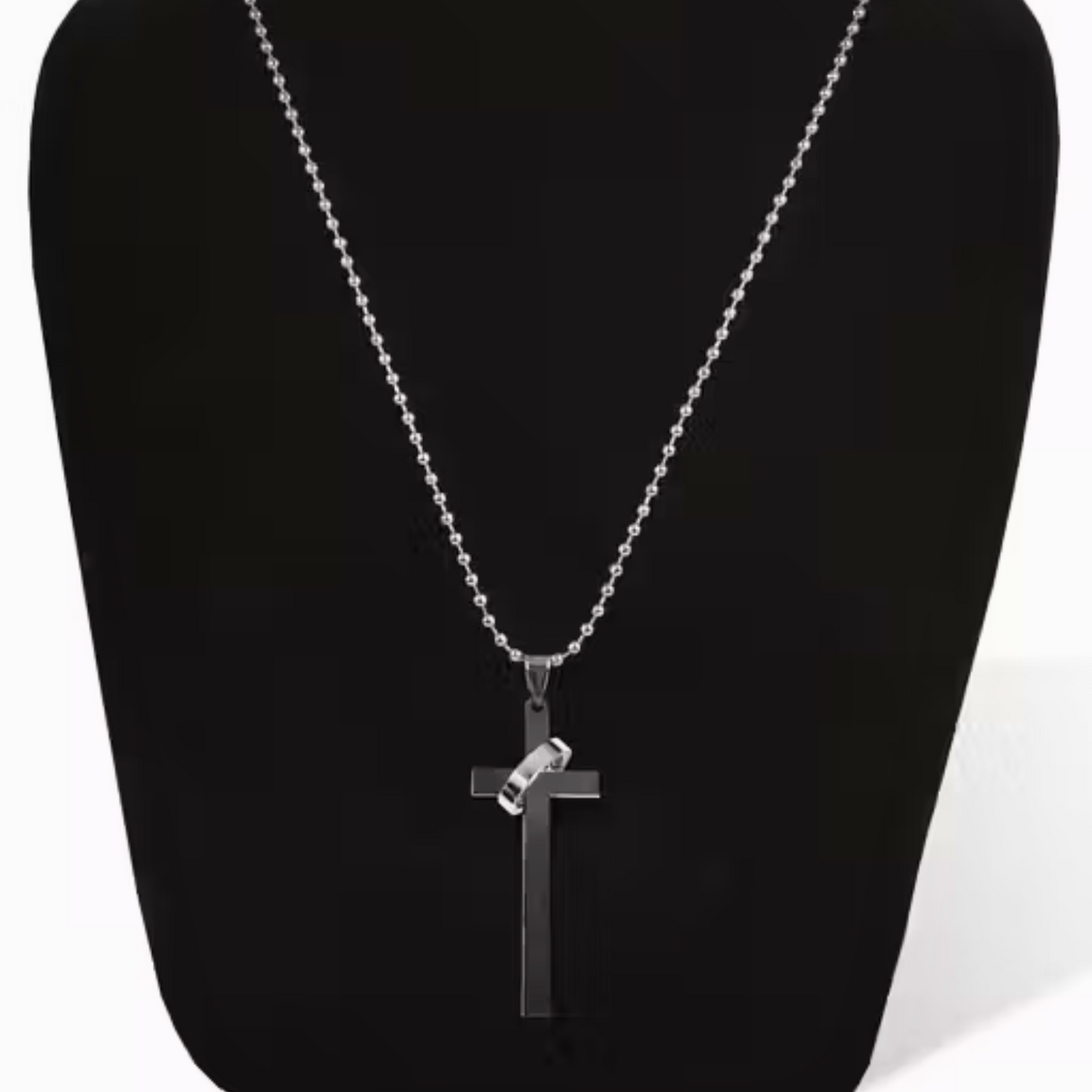 Silver cross necklace on a black stand with a white background