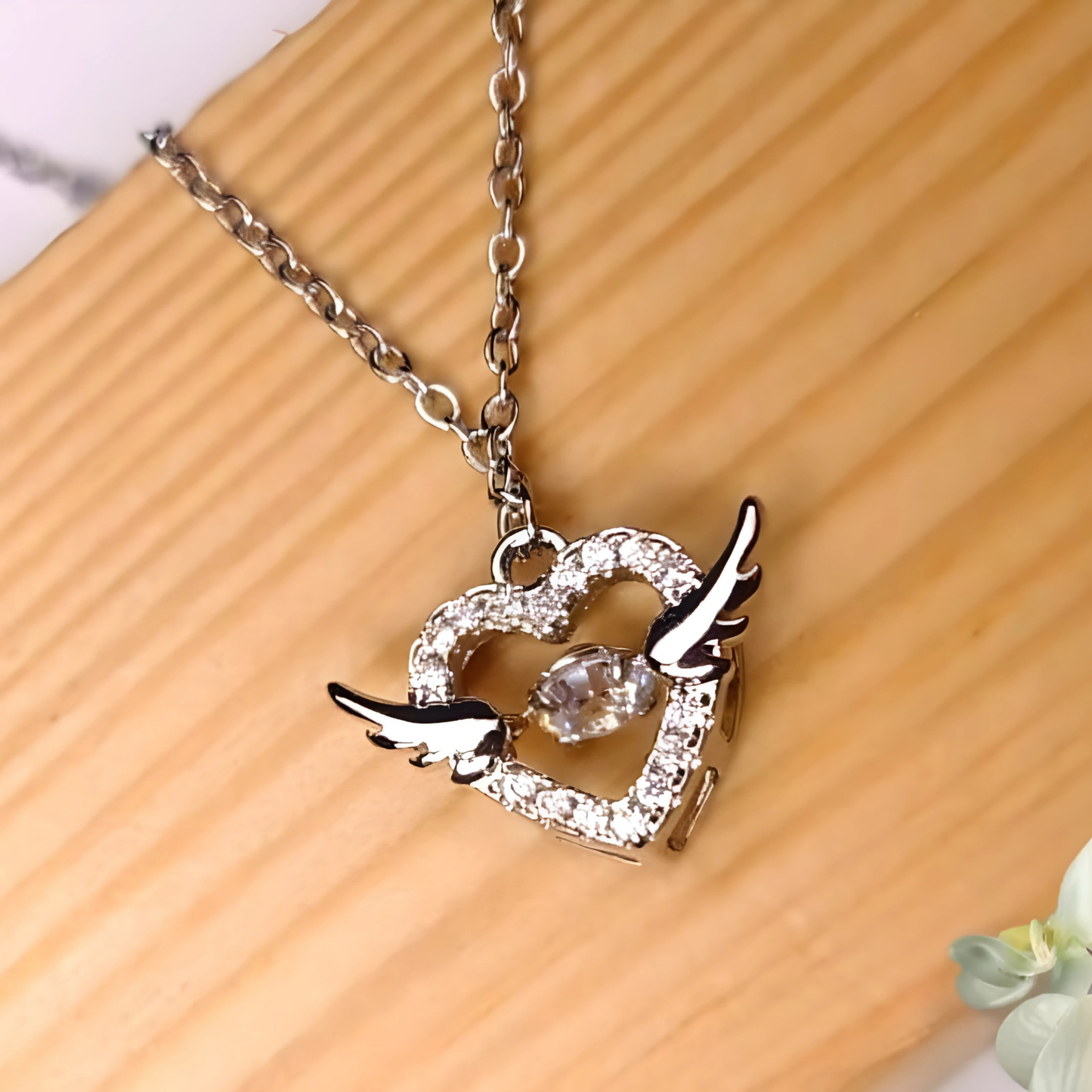 Silver necklace with a heart and bird pendant on a wooden surface