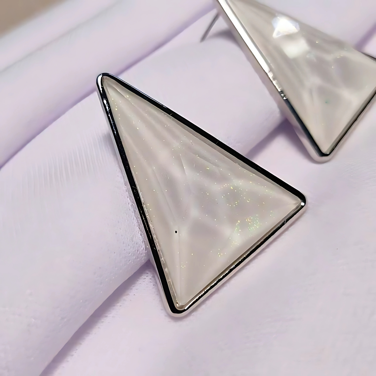 Triangular earrings with a metallic border on a light background