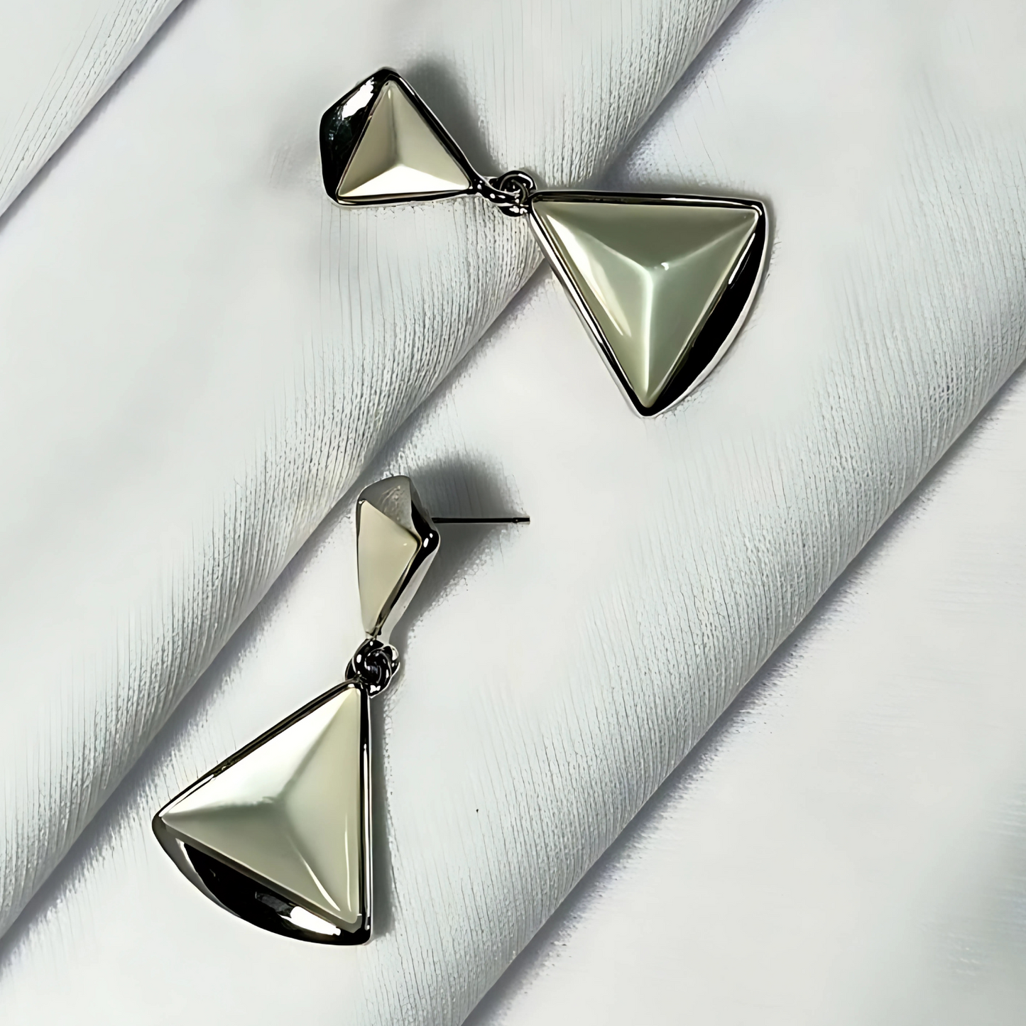 Pair of silver triangle earrings on a textured white surface