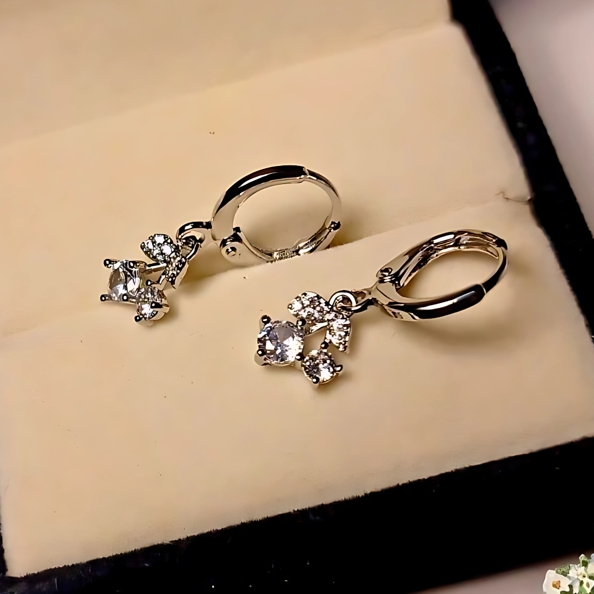 Silver hoop earrings with small gemstones on a beige jewelry box