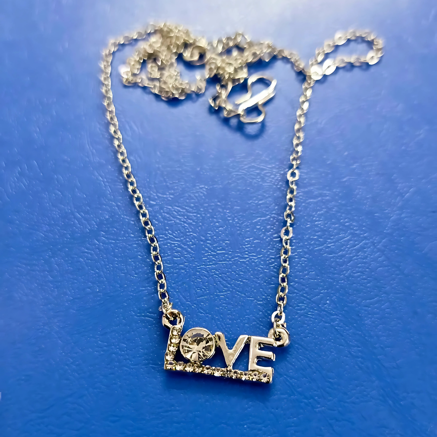 Gold 'LOVE' necklace on a blue background