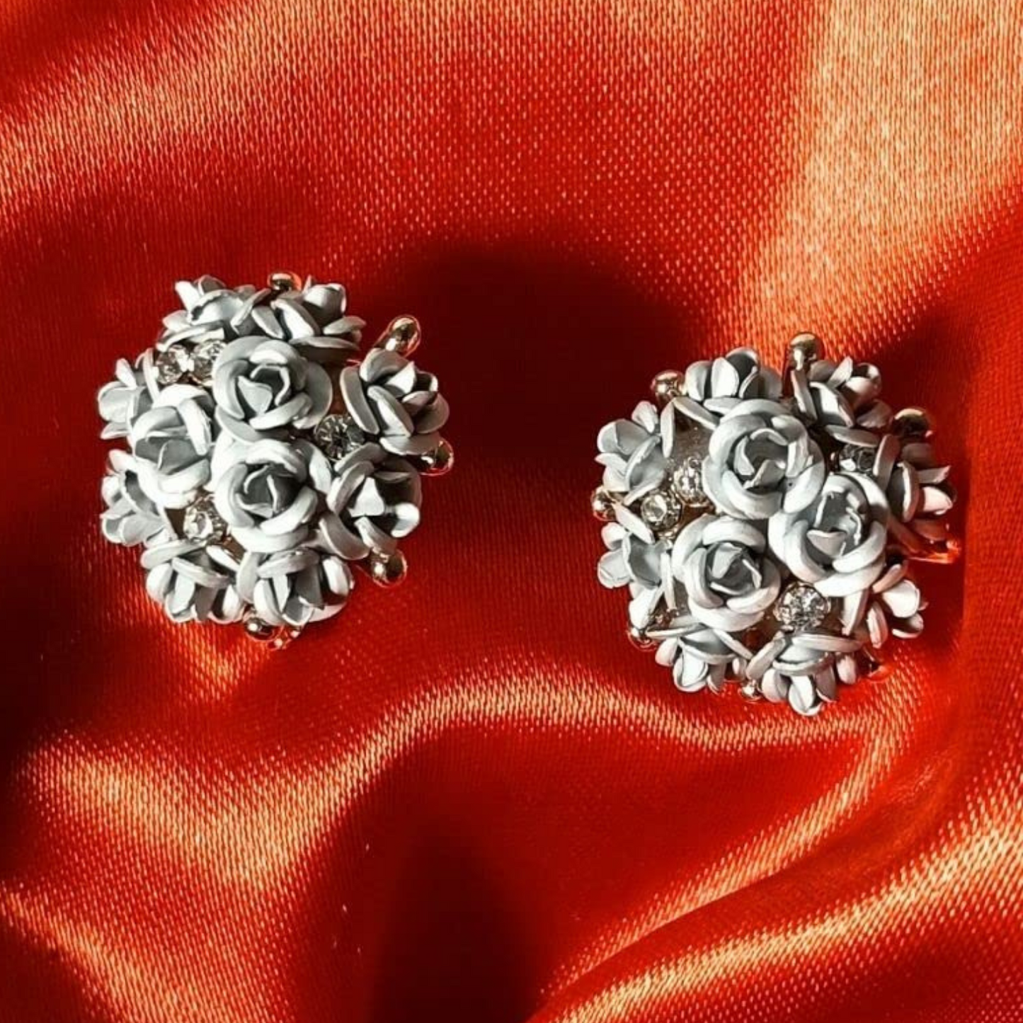 Silver floral earrings on a red satin background