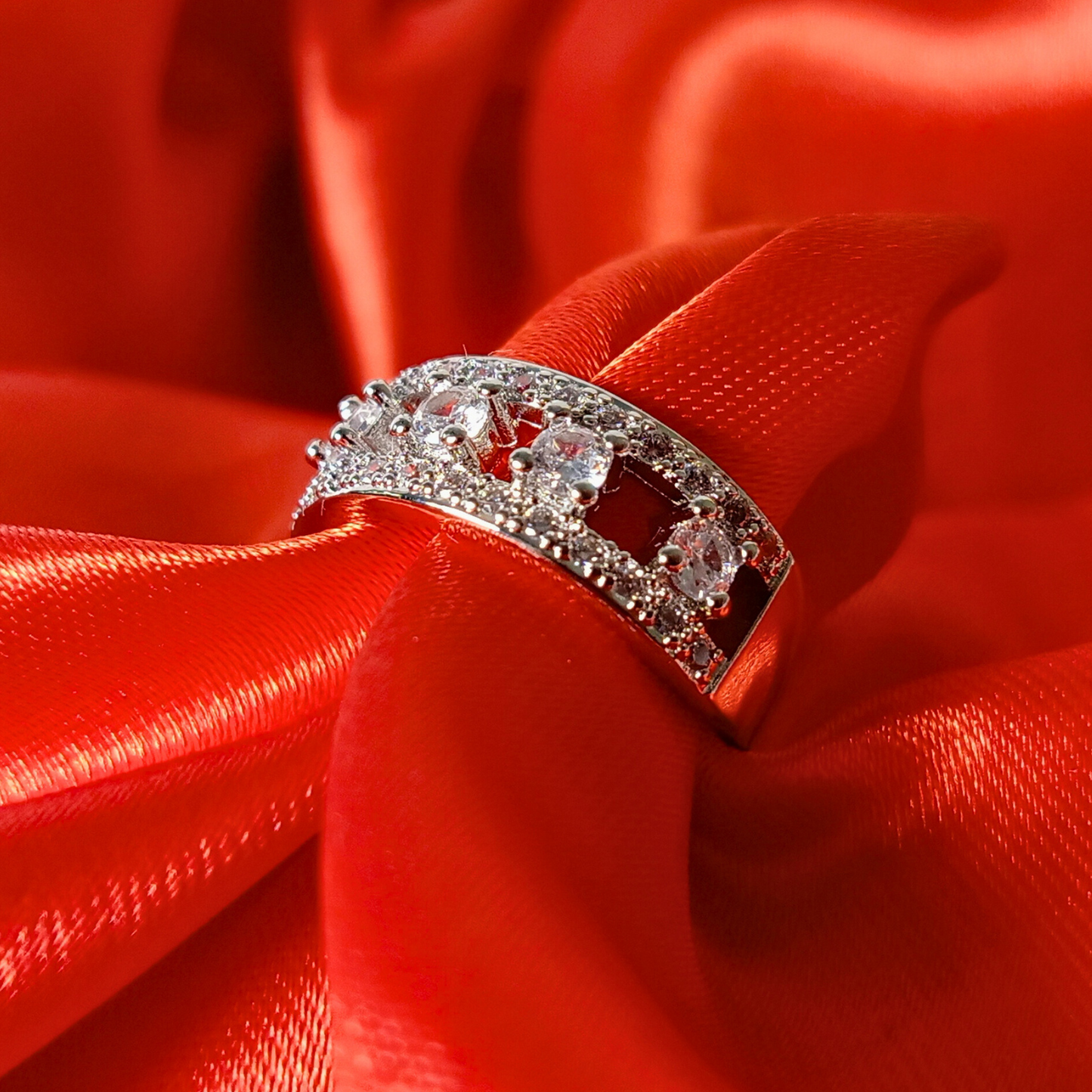 Silver ring with clear stones on a red fabric background