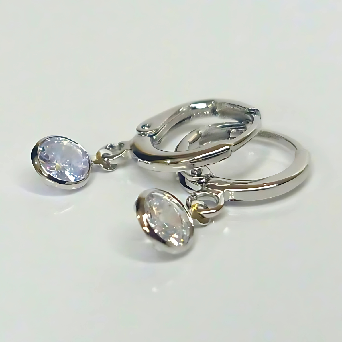 Pair of silver earrings with round gemstones on a white background