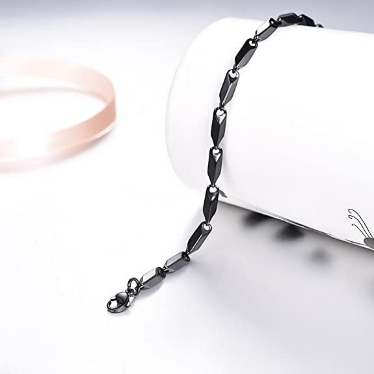 Black chain necklace on a white surface with a blurred background