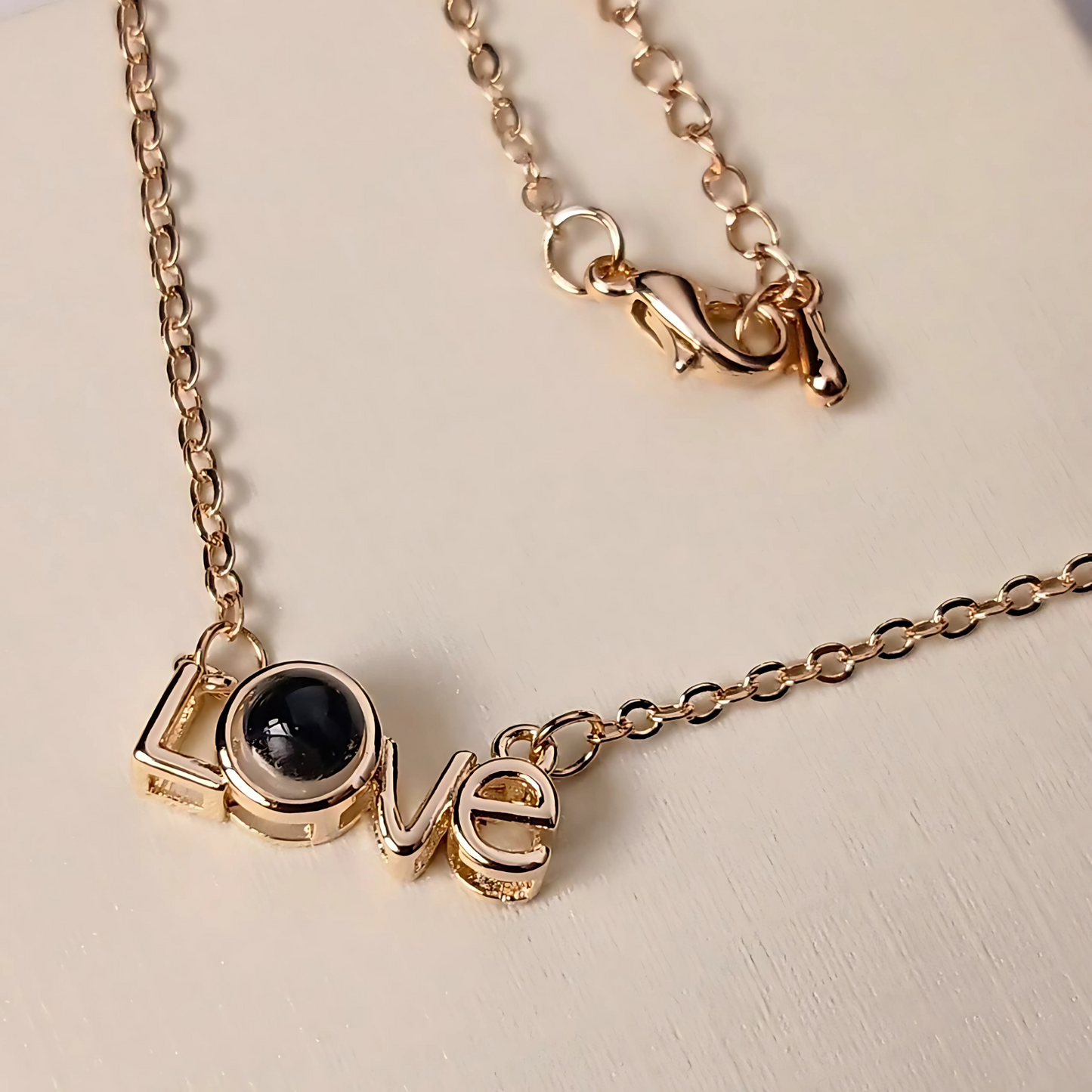 Gold necklace with 'LOVE' pendant on a light background