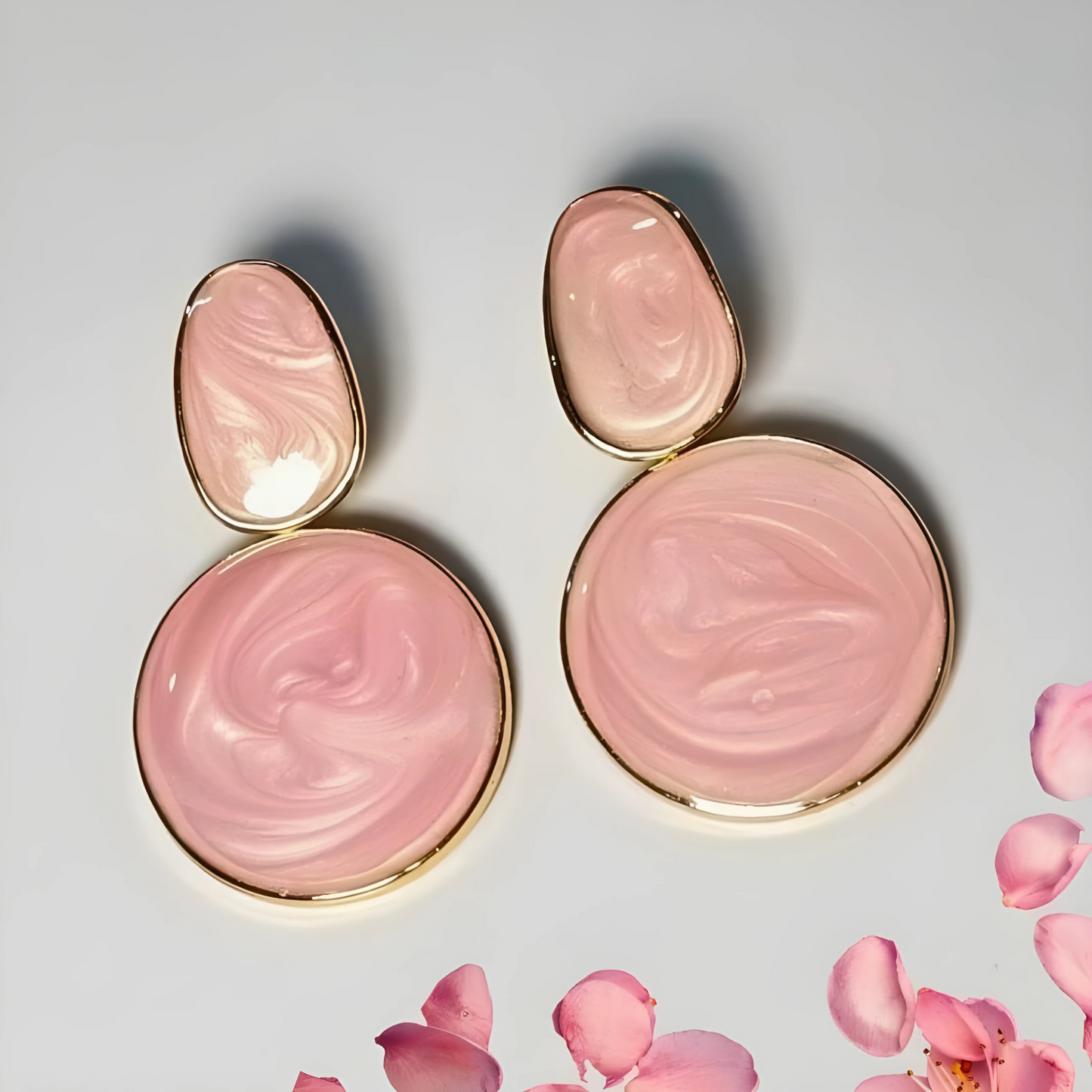 Pink makeup products with gold accents on a light gray background with pink petals.
