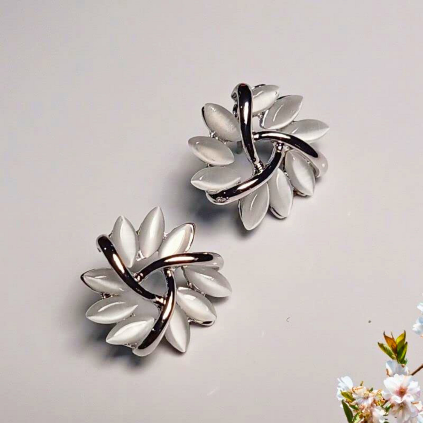 Pair of silver earrings with leaf-like design on a light gray background