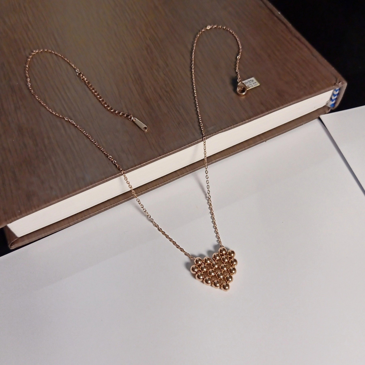 Rose gold necklace with a heart pendant on a wooden surface