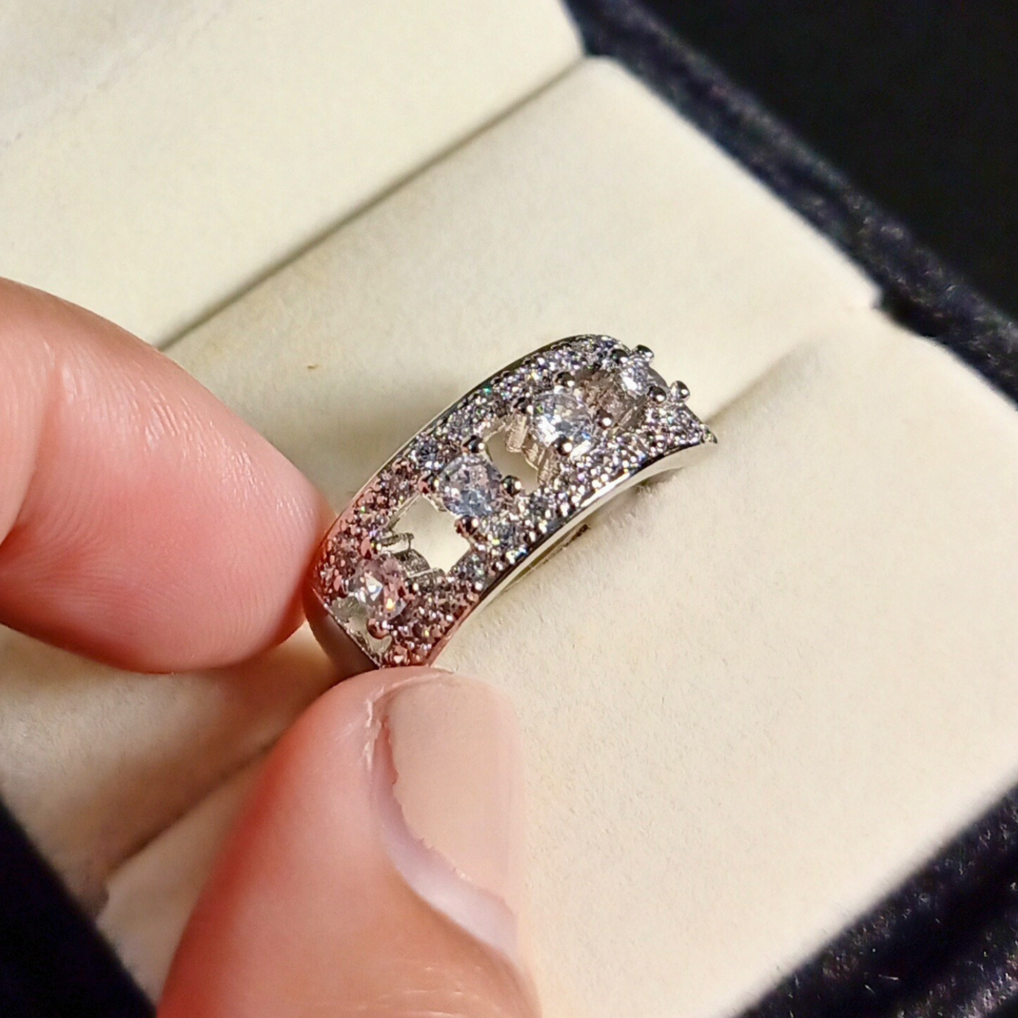 Close-up of a hand holding a diamond ring with a blurred background