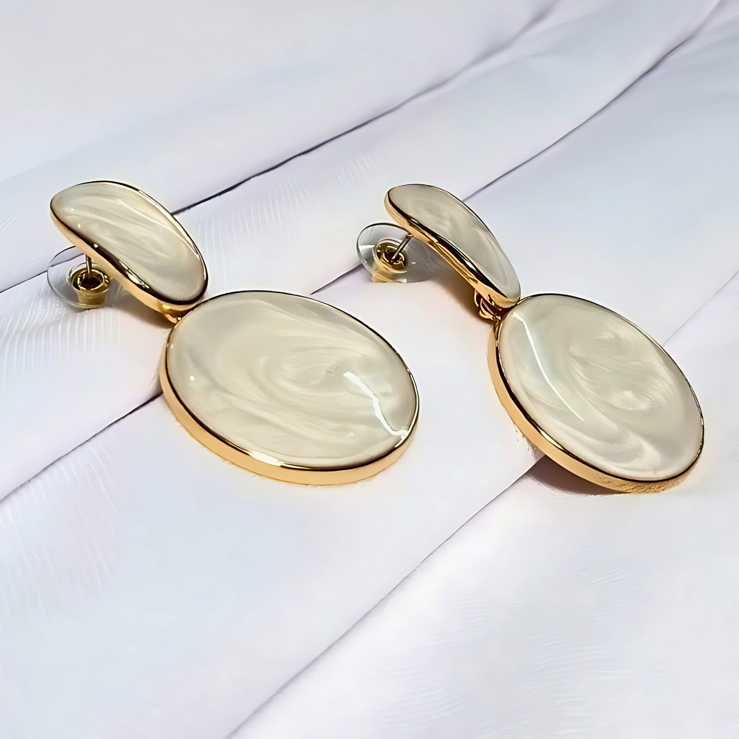 Pair of earrings with gold and beige stones on a white background