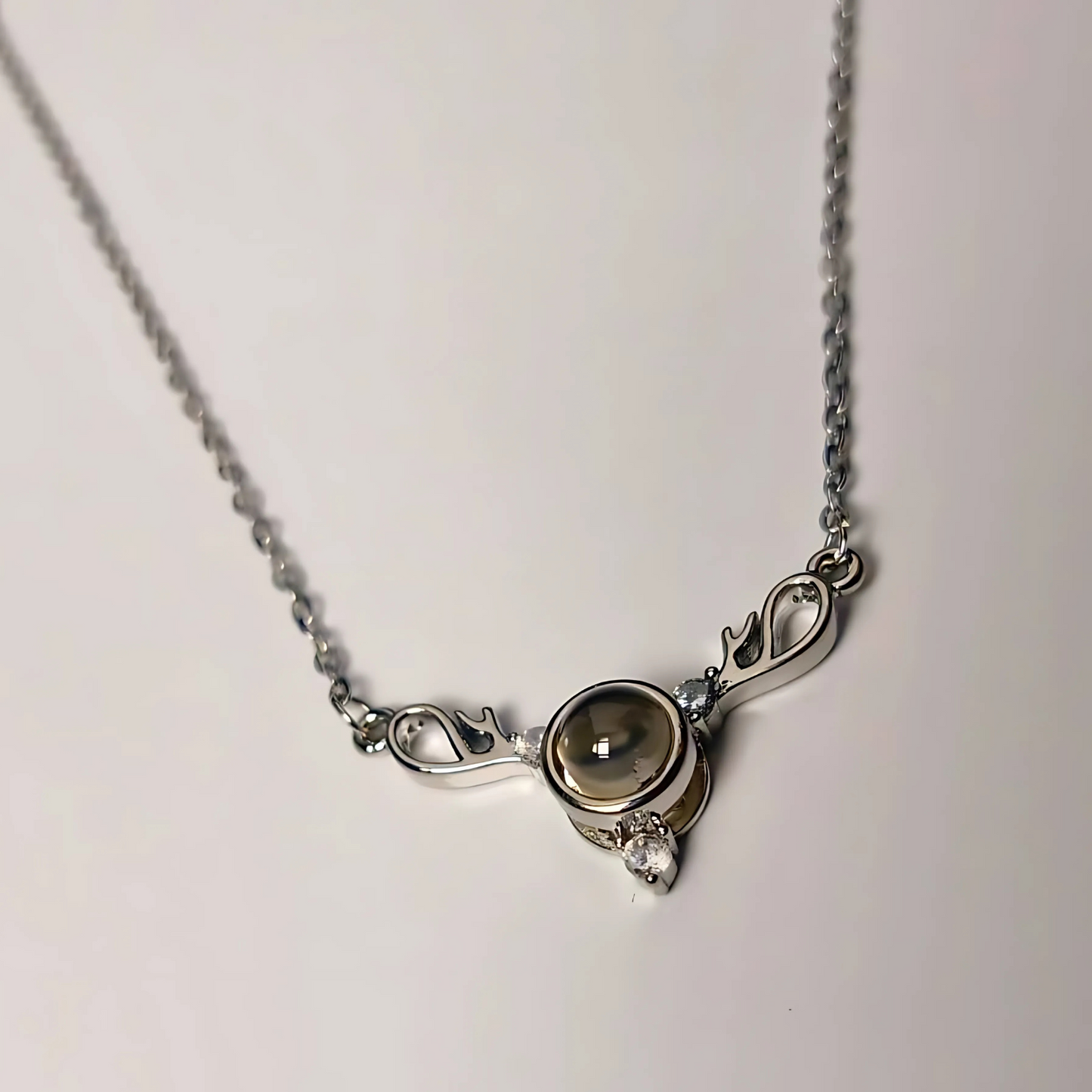 Silver necklace with a circular pendant on a light gray background