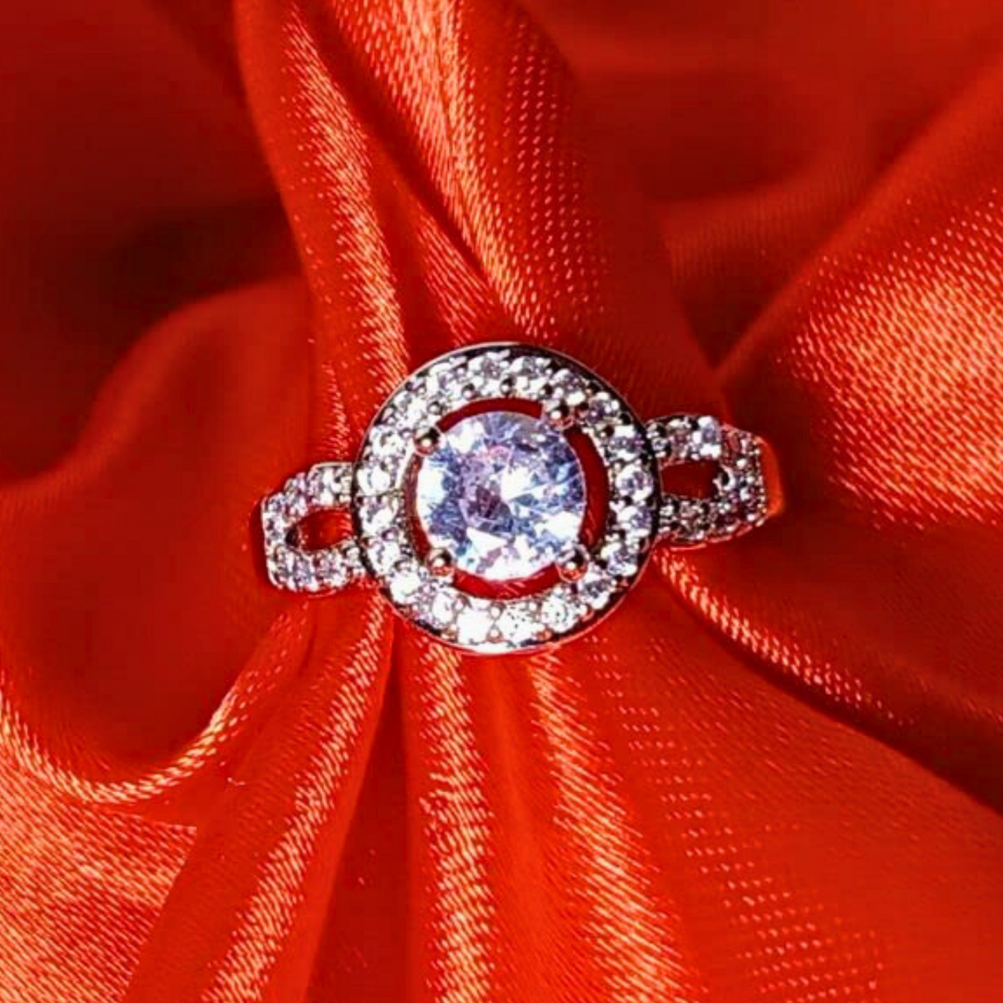 Silver ring with a large central gemstone on a red fabric background