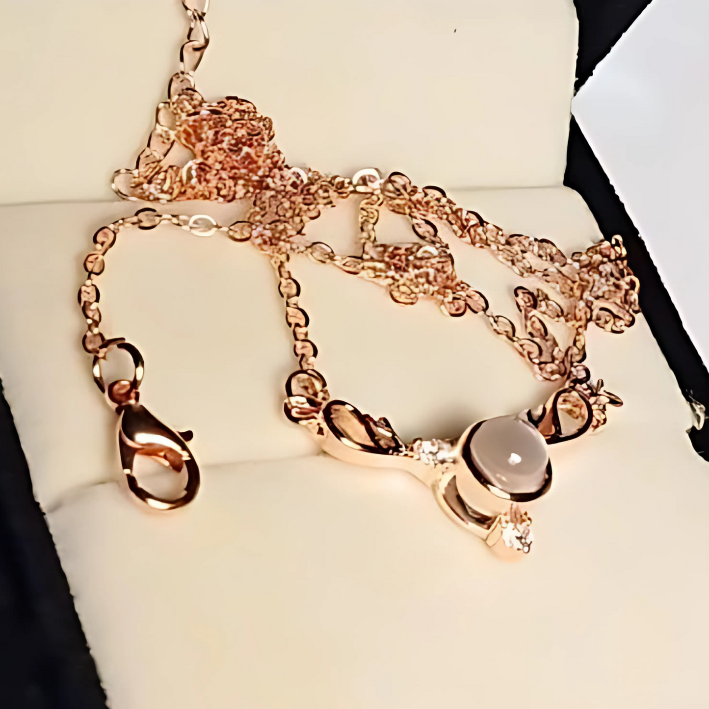 Rose gold necklace with a heart-shaped charm on a white cushion