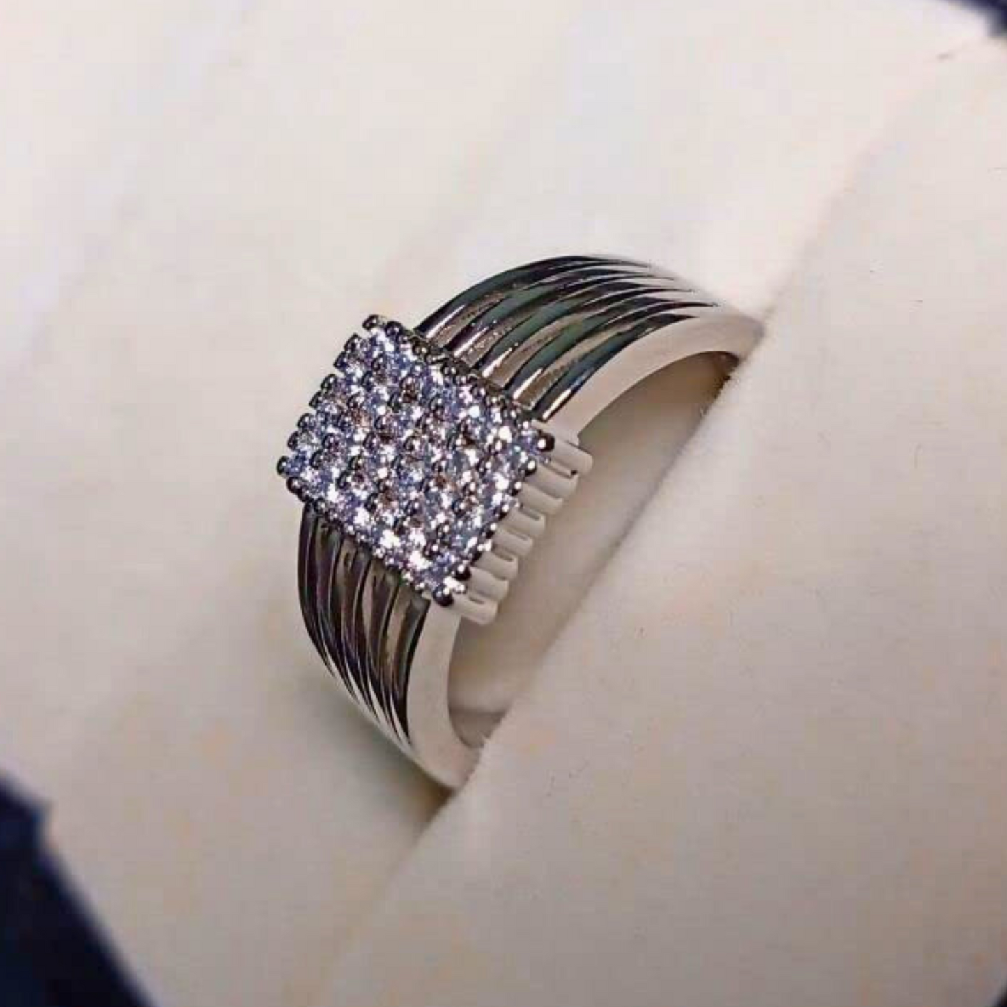 Silver ring with a diamond-shaped center on a white surface