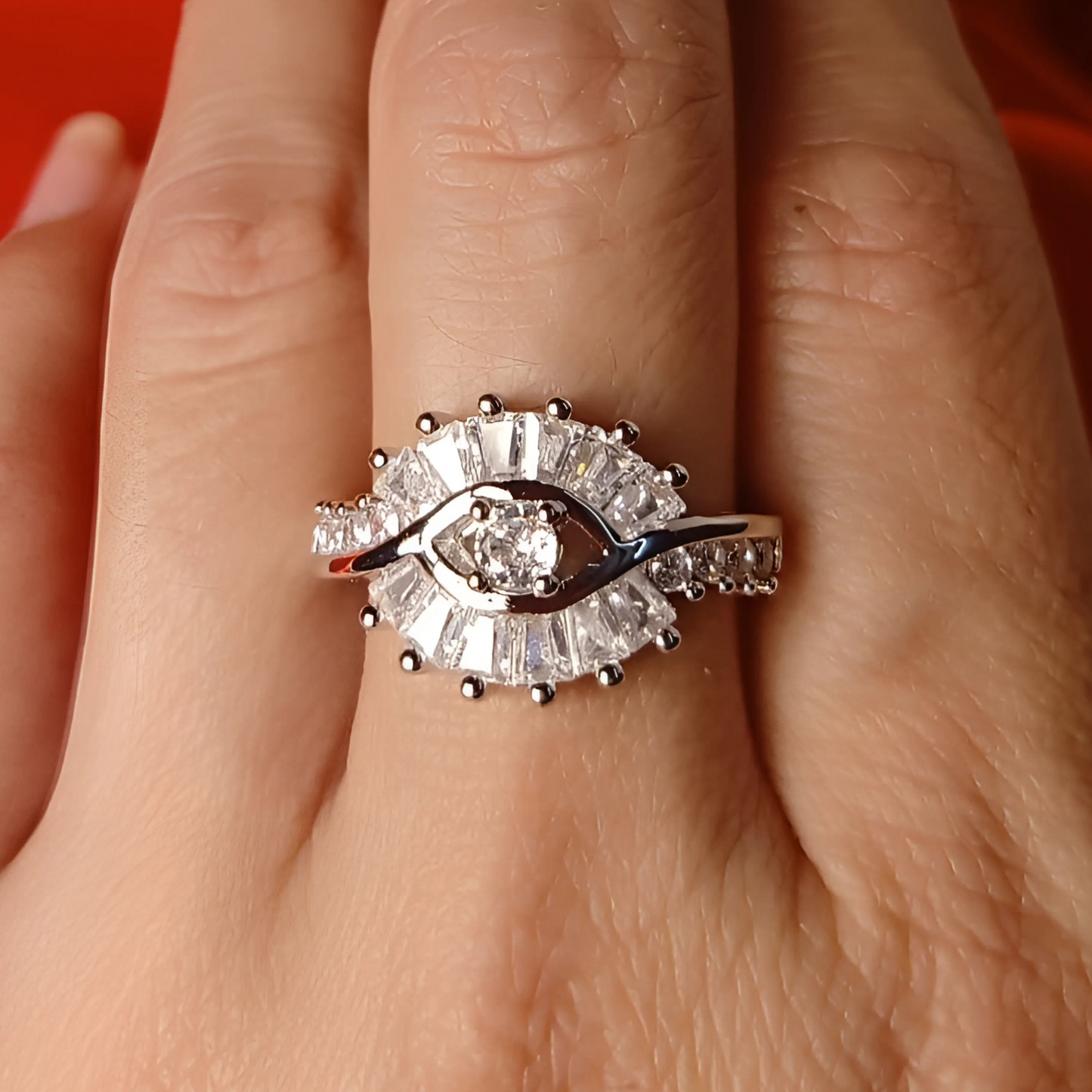Diamond ring on a person's finger with a red background