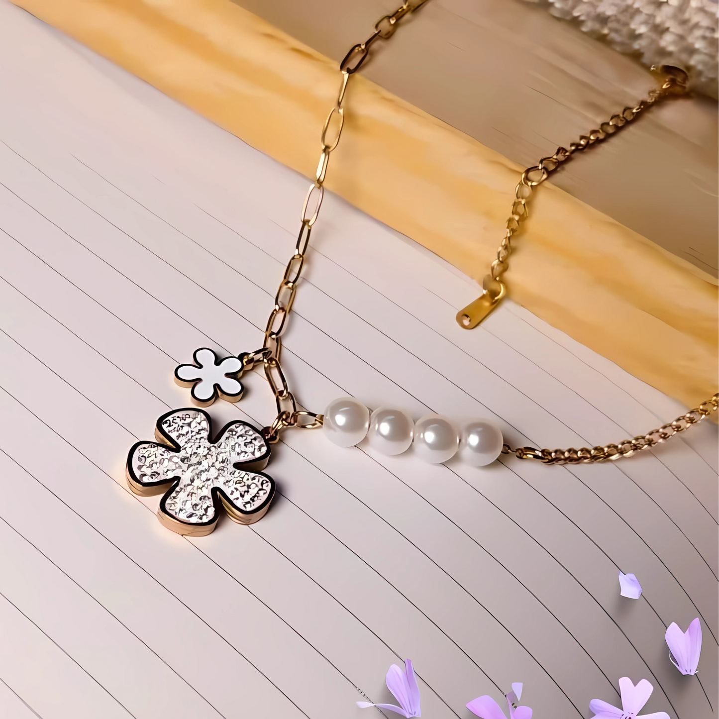 Gold necklace with a flower pendant and pearl beads on a lined paper background