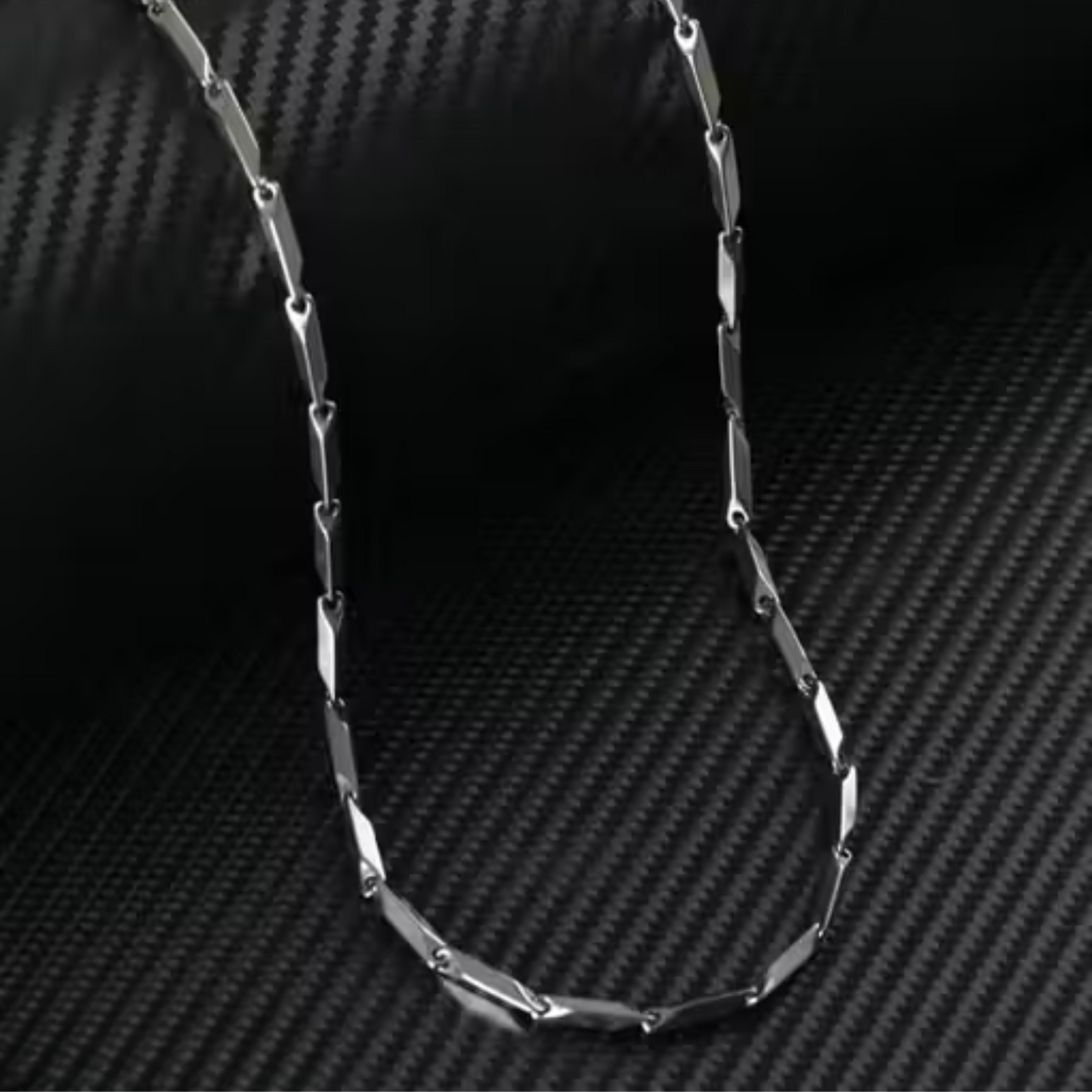 Silver chain necklace on a carbon fiber background