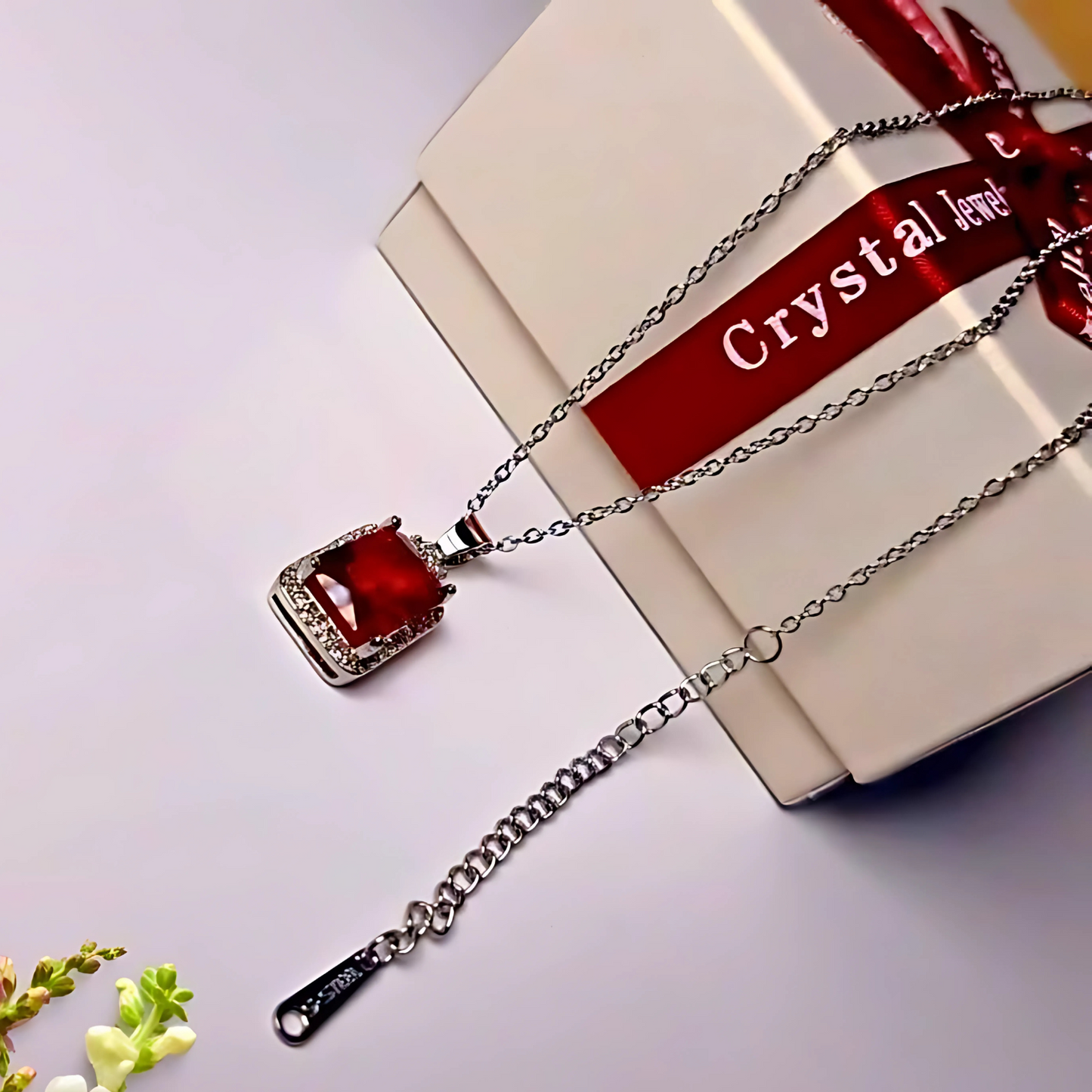 Pendant with red gemstone on a white surface with 'Crystal Jewel' ribbon.