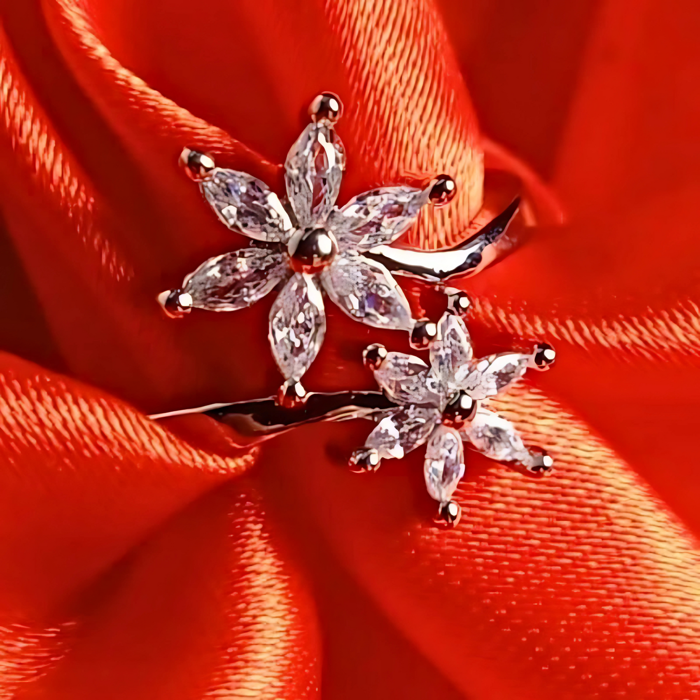 Silver flower-shaped earrings with clear stones on a red fabric background