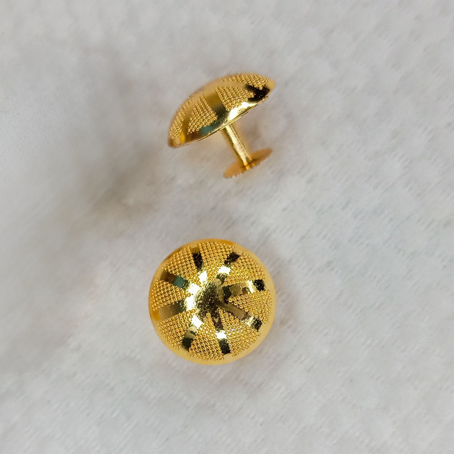 Gold textured button stud on a white background