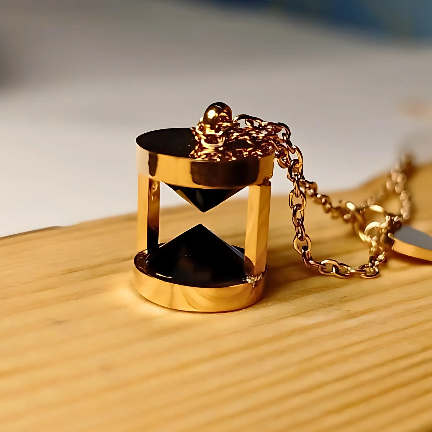 Gold hourglass pendant on a wooden surface