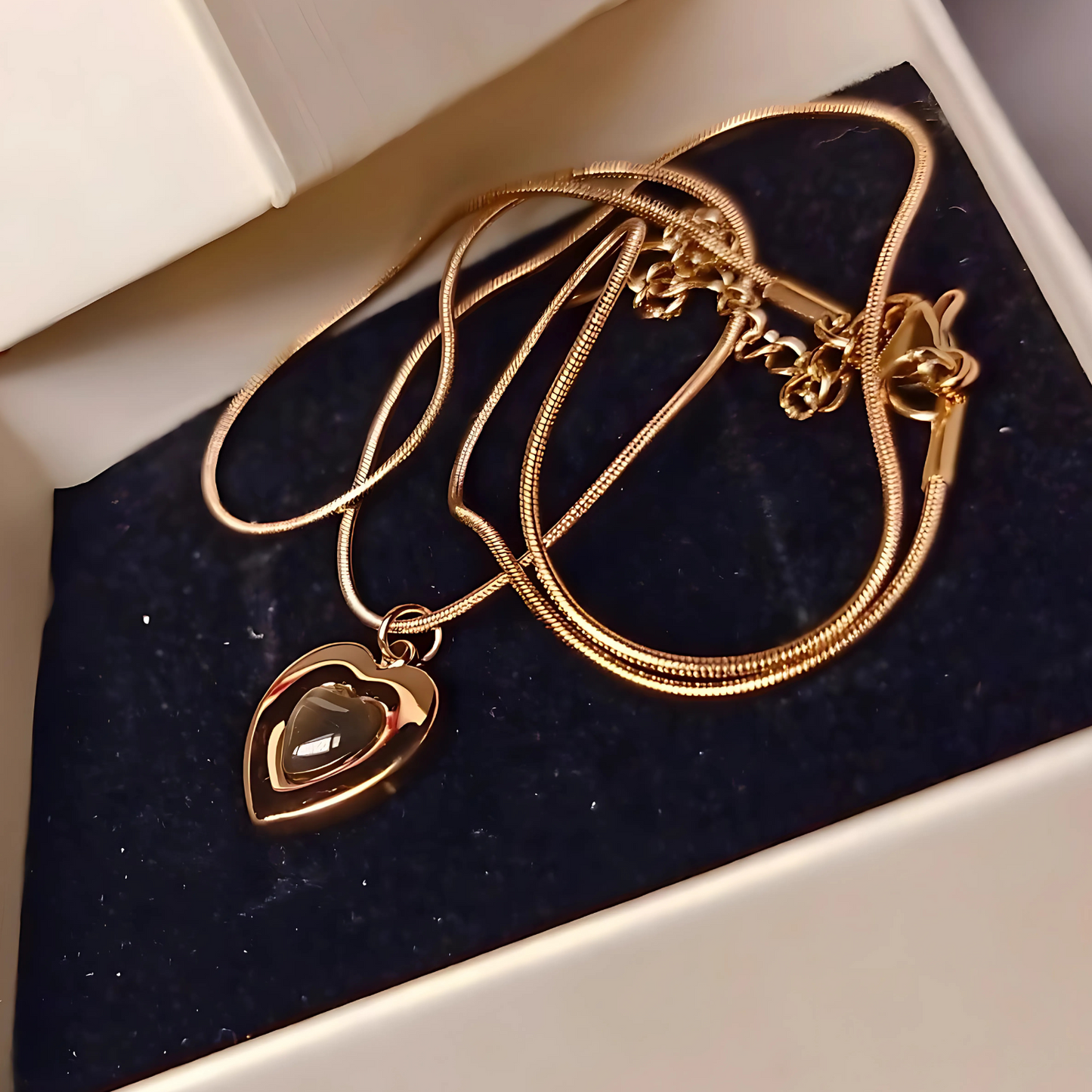 Gold necklace with a heart-shaped pendant on a dark blue velvet surface.