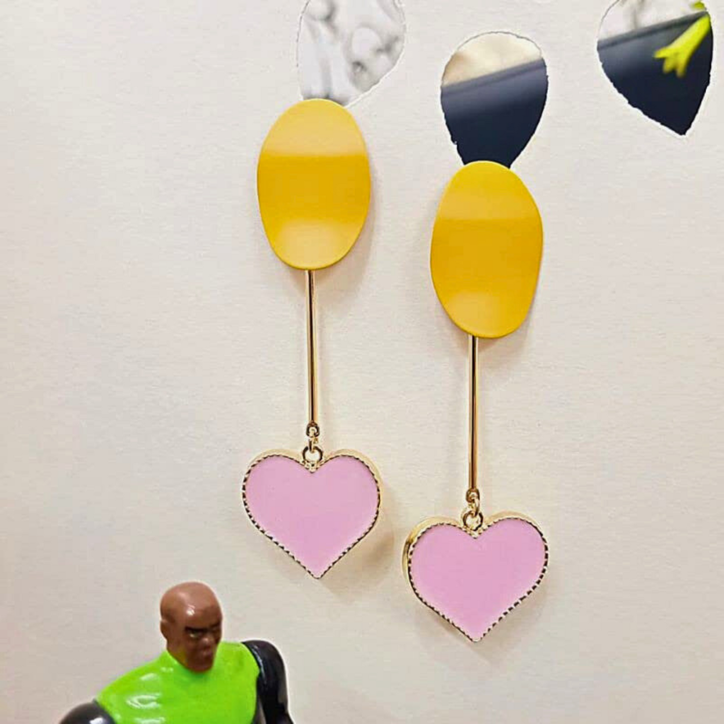 Earrings with pink heart-shaped pendants and yellow oval tops on a white background