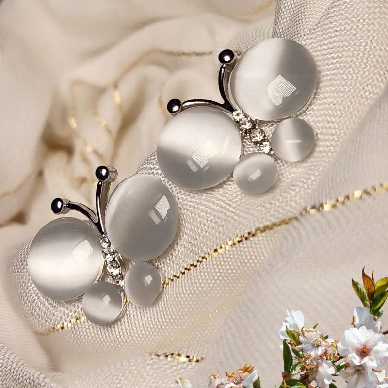 Silver butterfly-shaped earring with white stones on a soft fabric background