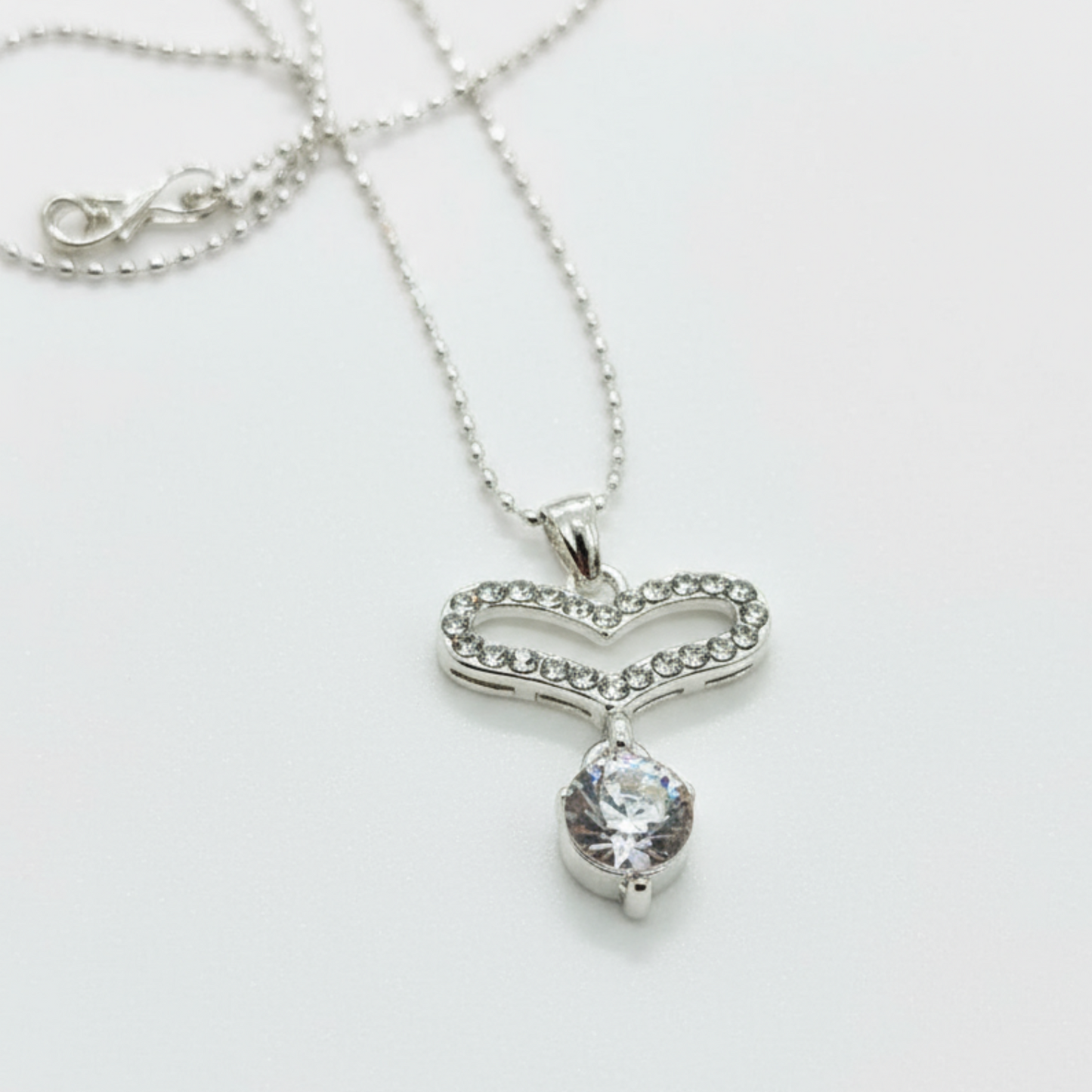 Silver necklace with a heart-shaped pendant on a white background