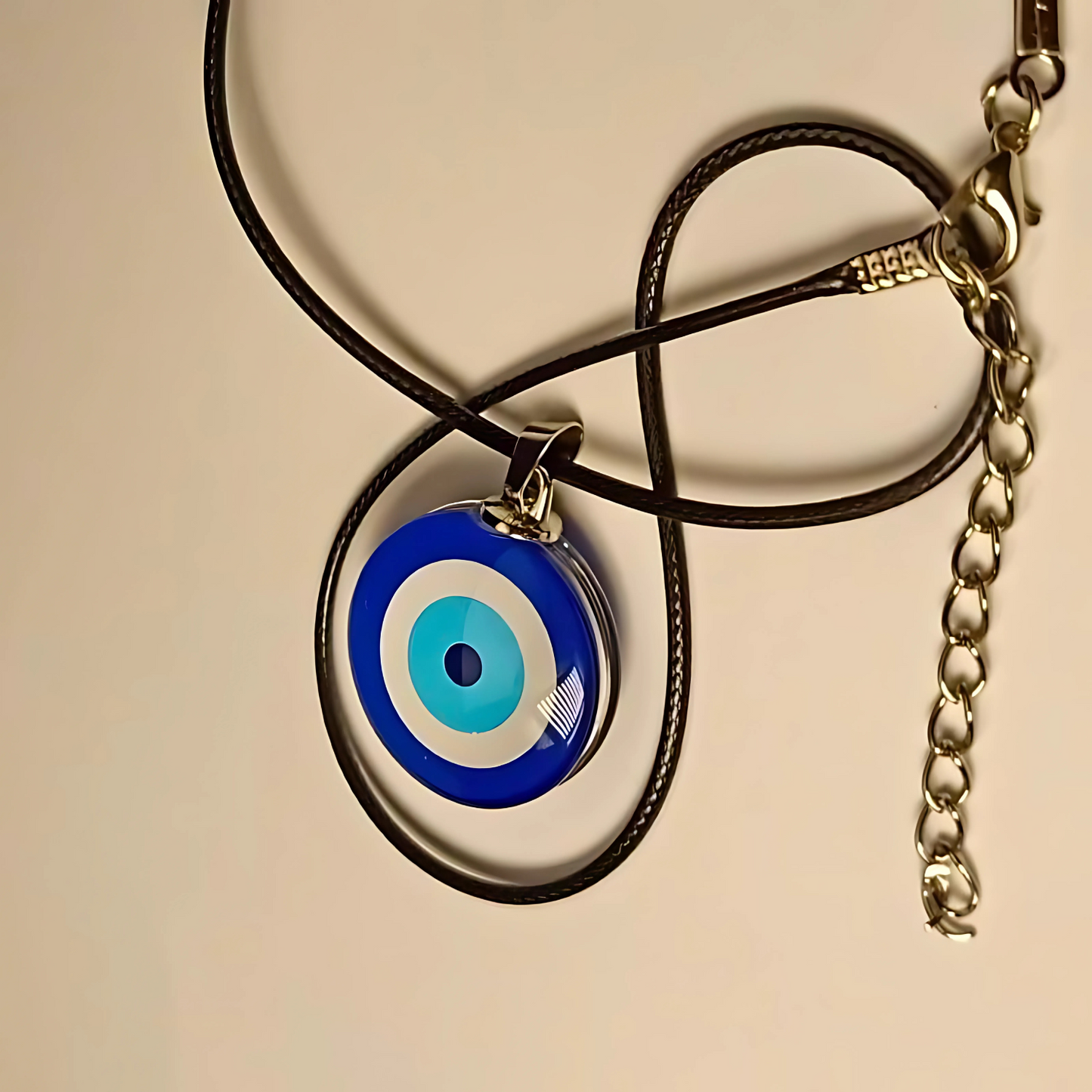 Necklace with a blue evil eye pendant on a beige background