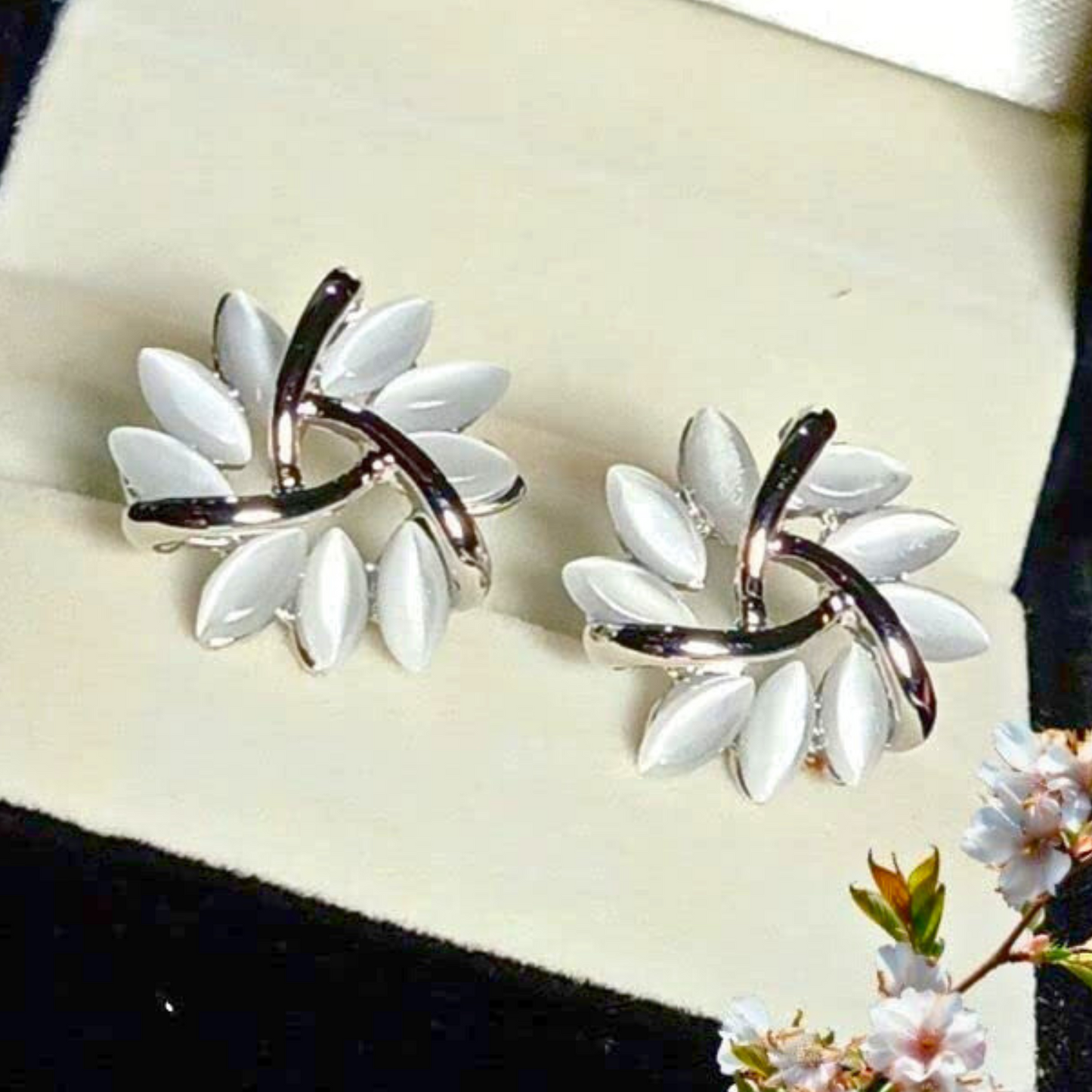 Pair of white floral earrings on a black and white background with flowers.