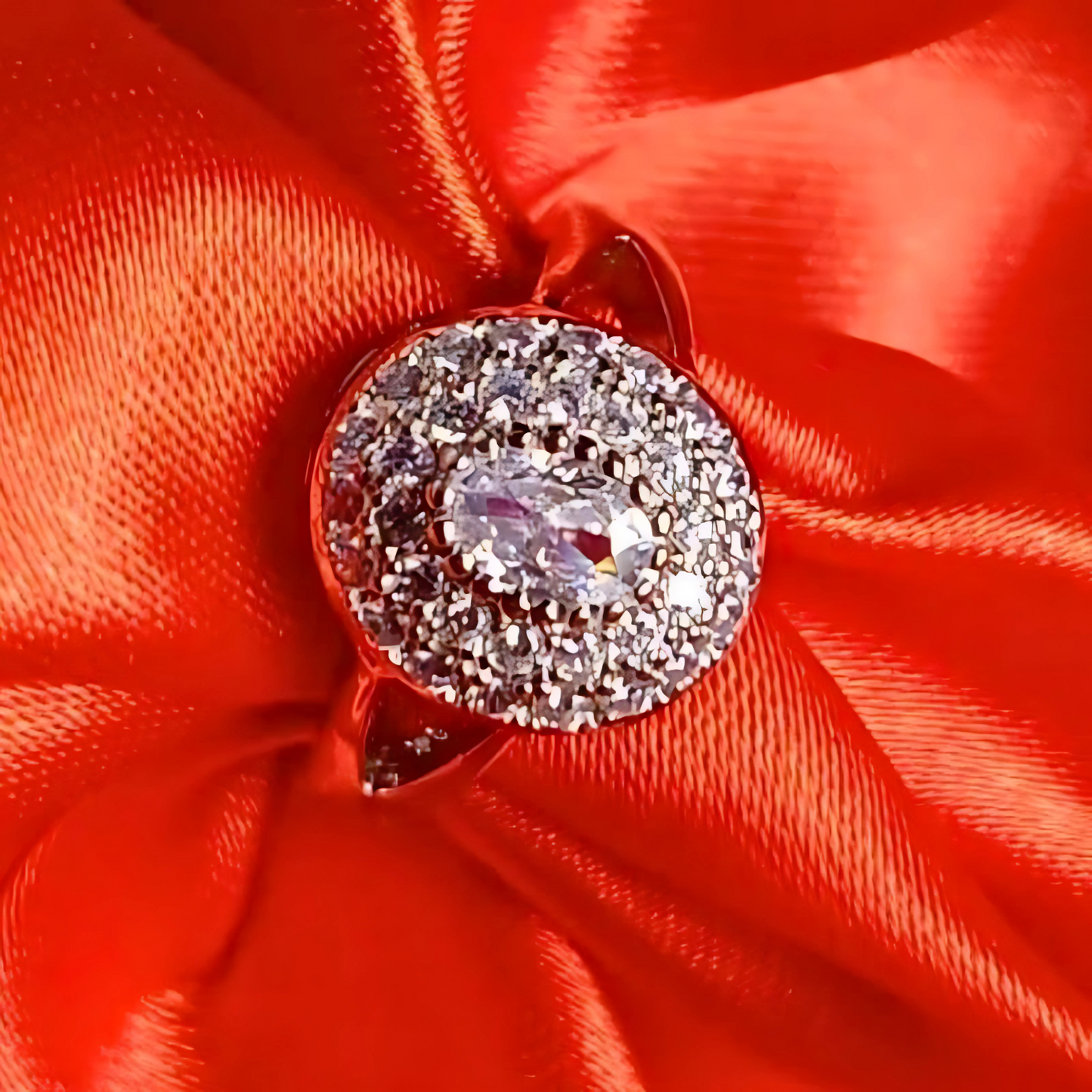 Silver brooch with clear gemstone on a red satin background