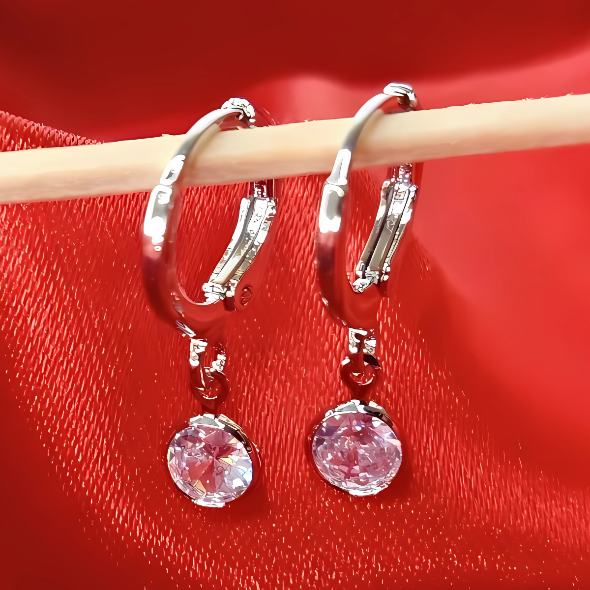 Silver hoop earrings with pink gemstones on a red background