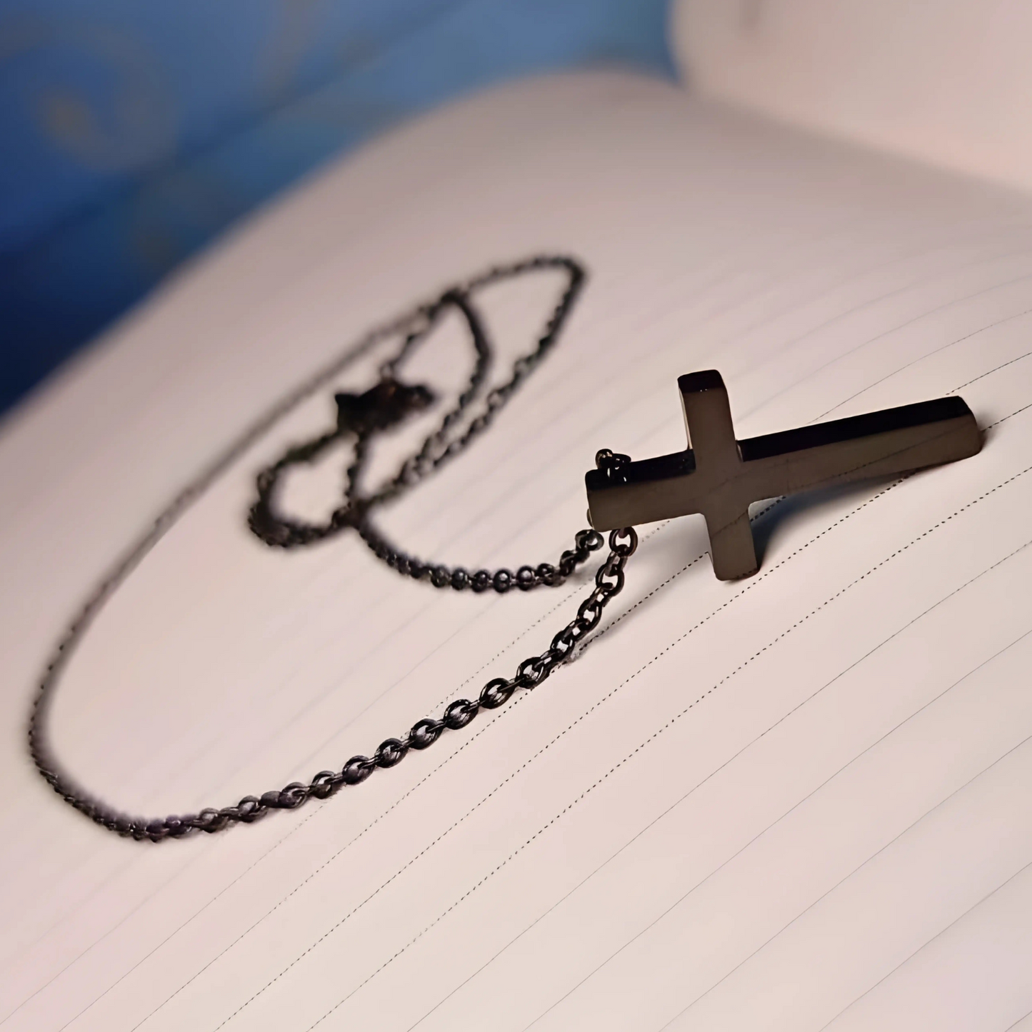 Black cross necklace on a piece of lined paper