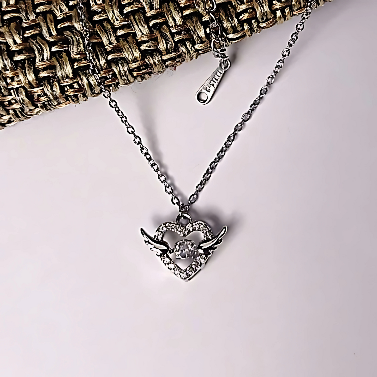 Silver necklace with a heart-shaped pendant on a light background