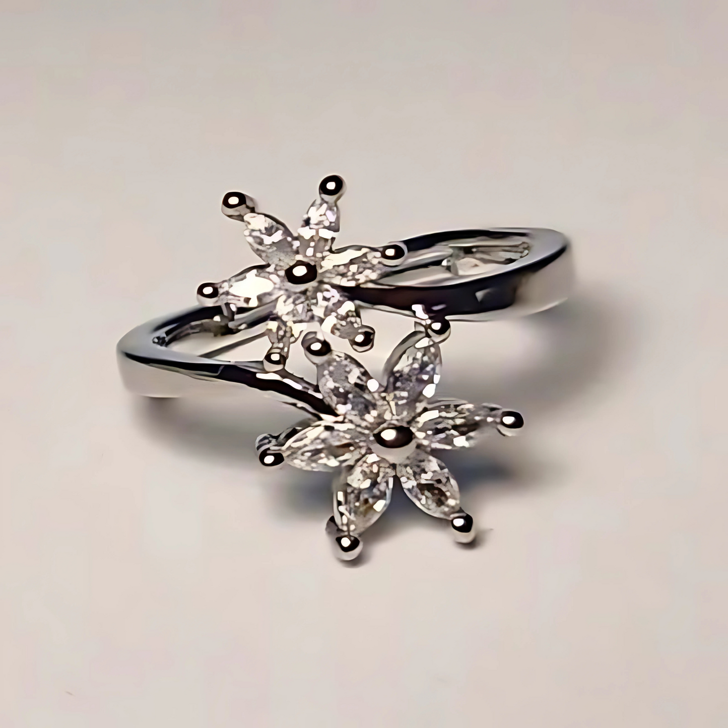 Silver ring with star-shaped gemstones on a light gray background