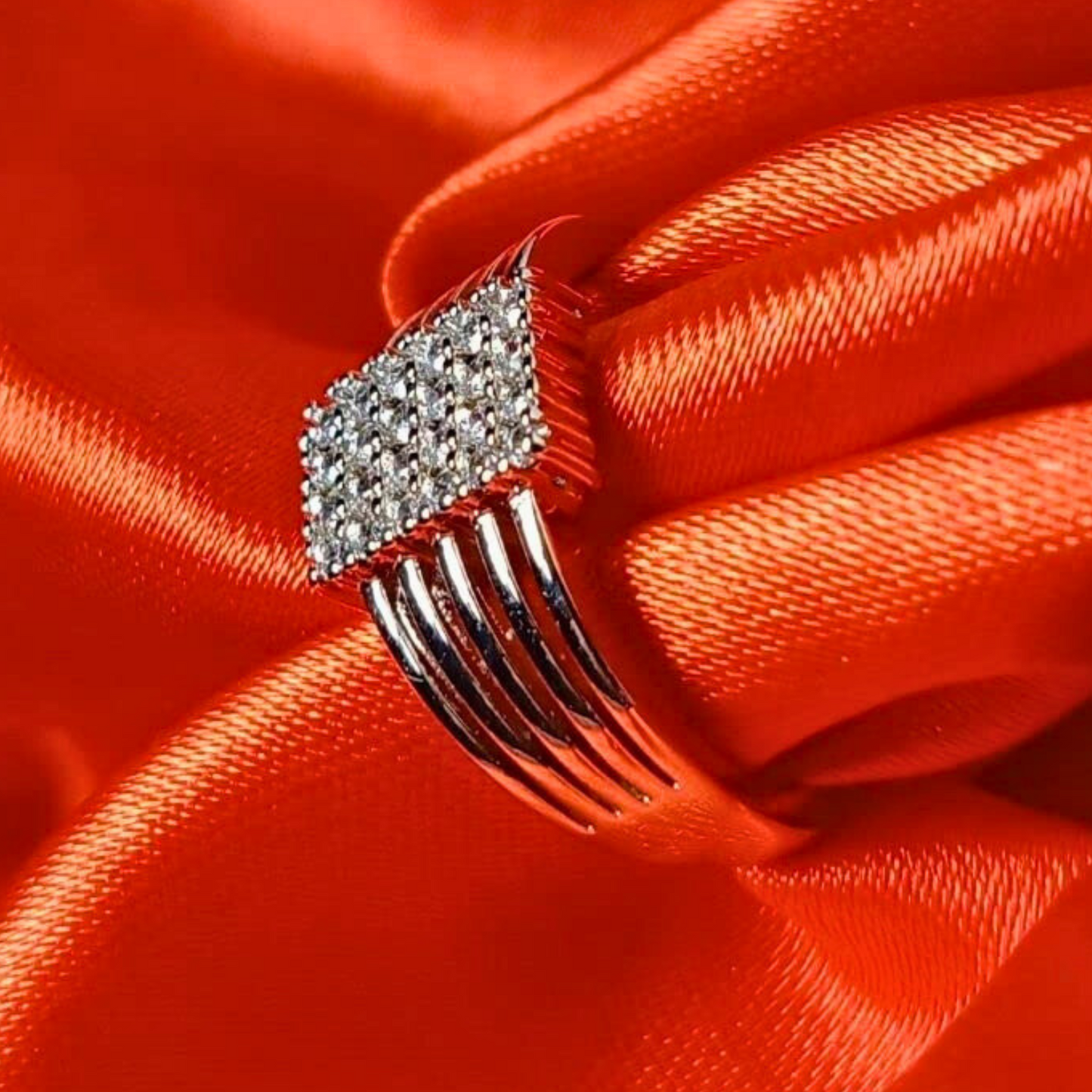 Silver comb-shaped hair clip with clear stones on a red satin background