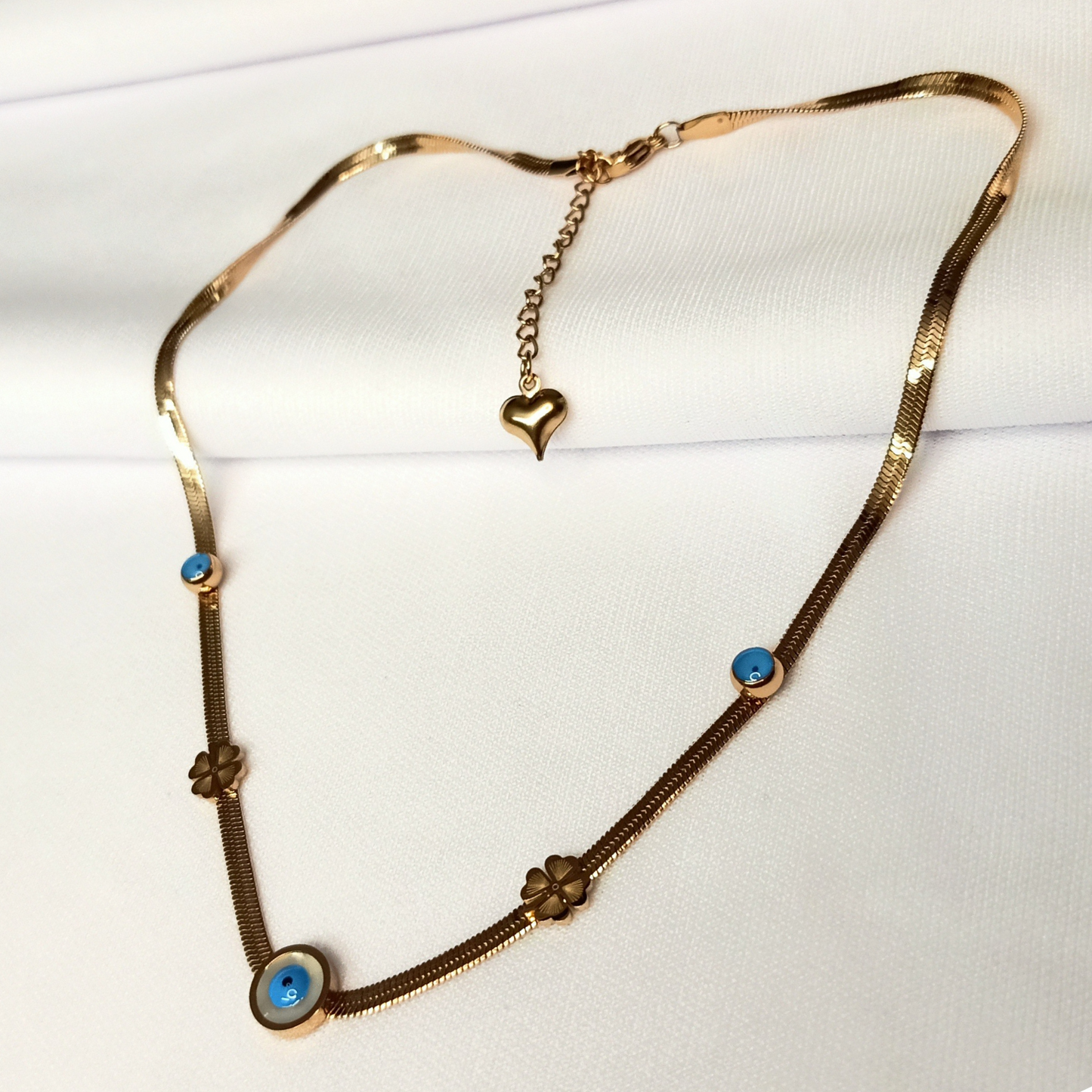 Gold necklace with blue stones and heart pendant on a white background