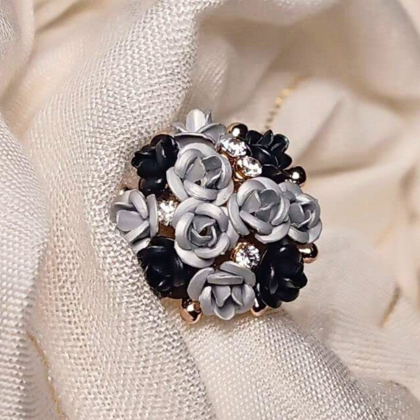 Floral brooch with black and white flowers on a textured beige background