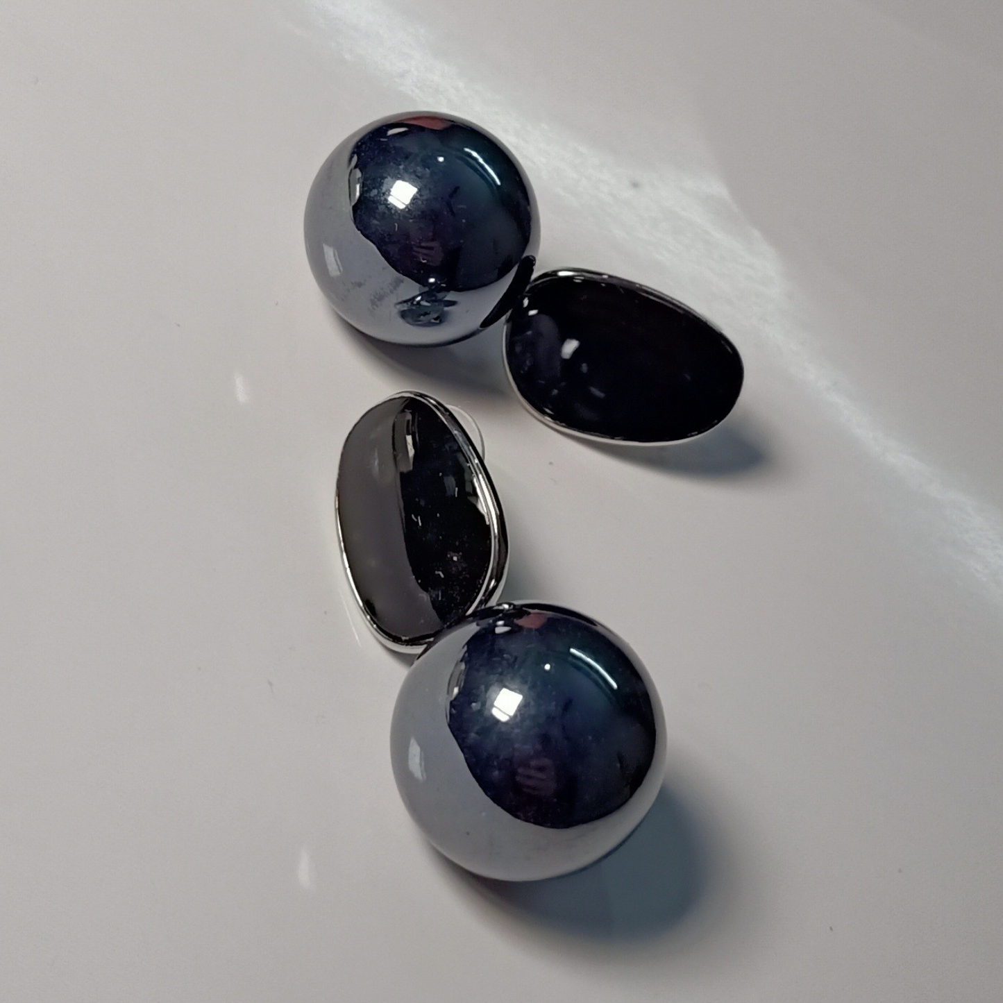 Pair of silver earrings with dark black stones on a white surface