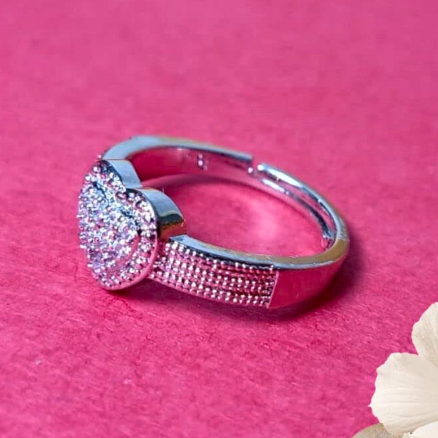 Silver ring with pink gemstones on a pink background