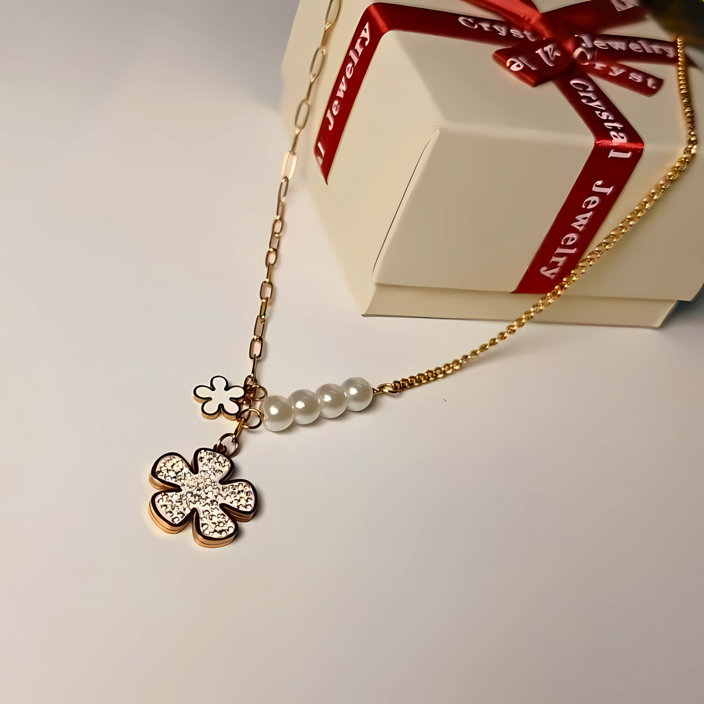 Gold necklace with a clover pendant and pearl beads in front of a Crystal Jewelry box.