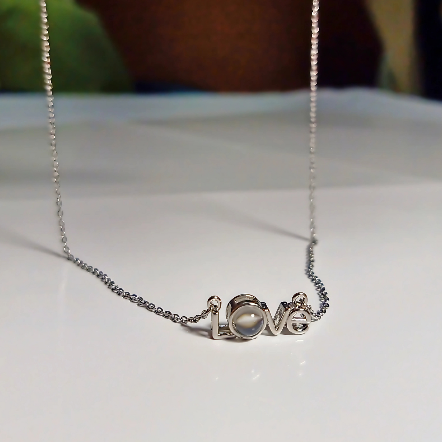 Silver necklace with 'LOVE' pendant on a white surface