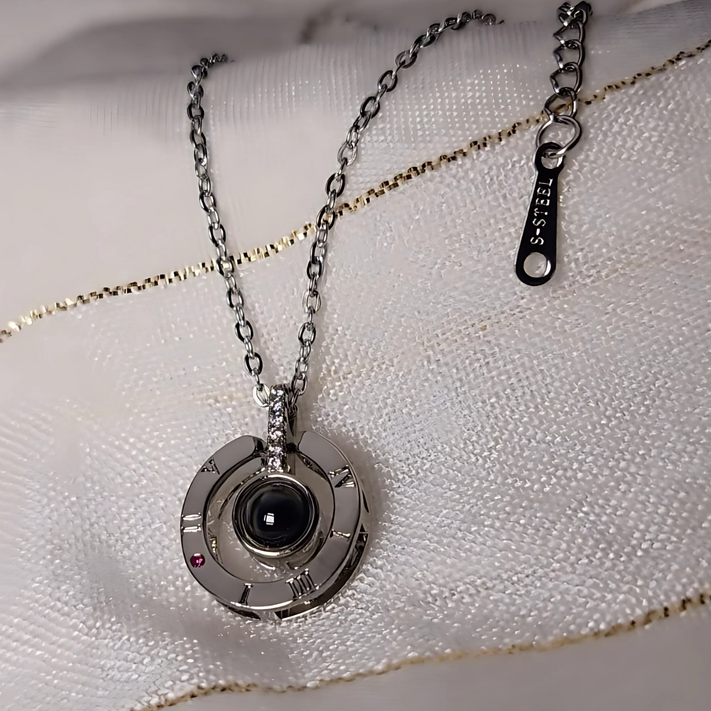 Silver necklace with a unique pendant on a white fabric background